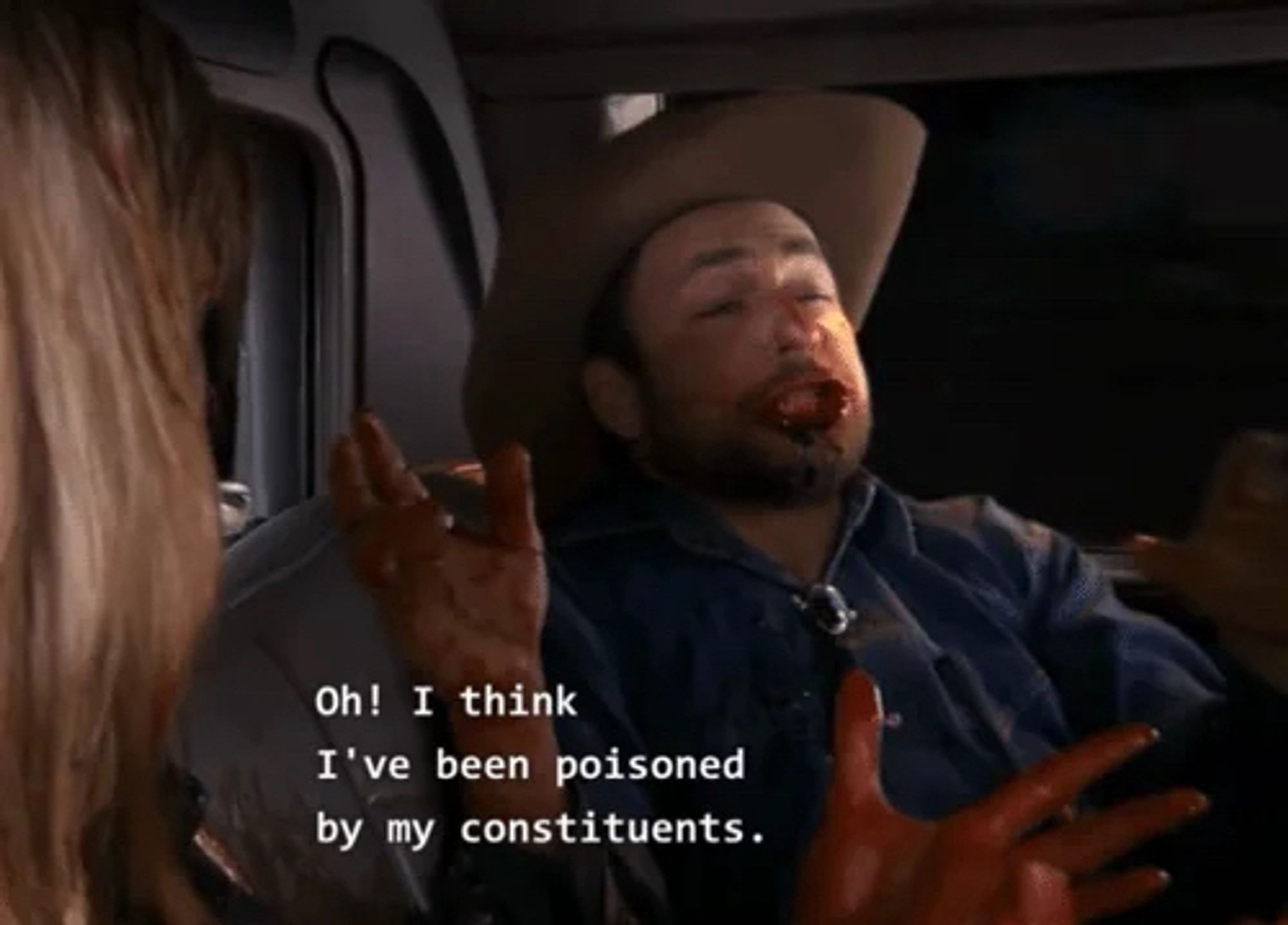 a frame from its always sunny in Philadelphia of charlie day, a brunette man with some scruff, is sitting in a vehicle in a cowboy hat and blue shirt looking ill and covered in blood. it has text that says “oh! i think i’ve been poisoned by my constituents.”