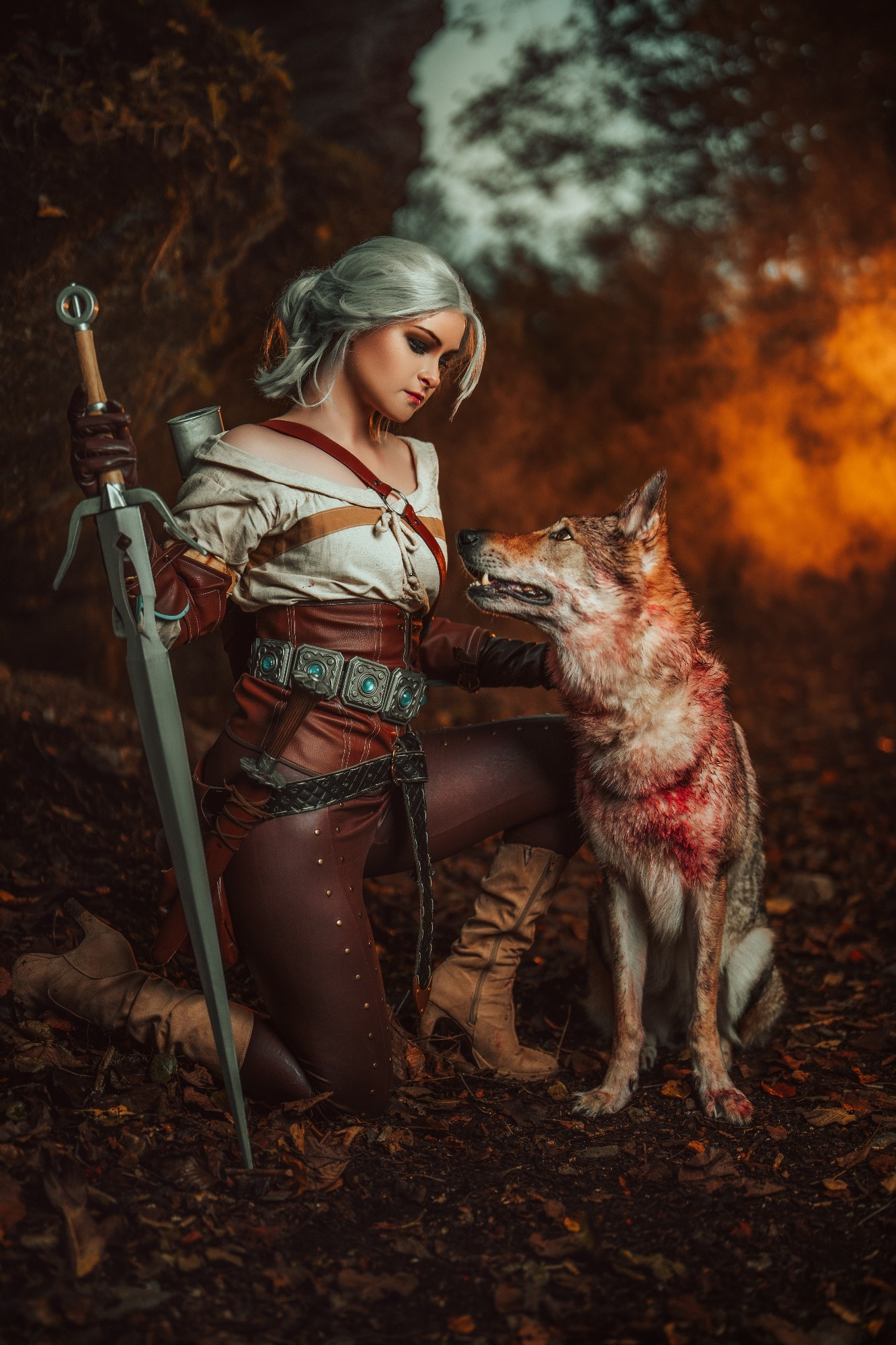 High quality cosplay photography of Cirilla from the Witcher franchise posing kneeling on the floor with a sword and a trusty wolf companion.