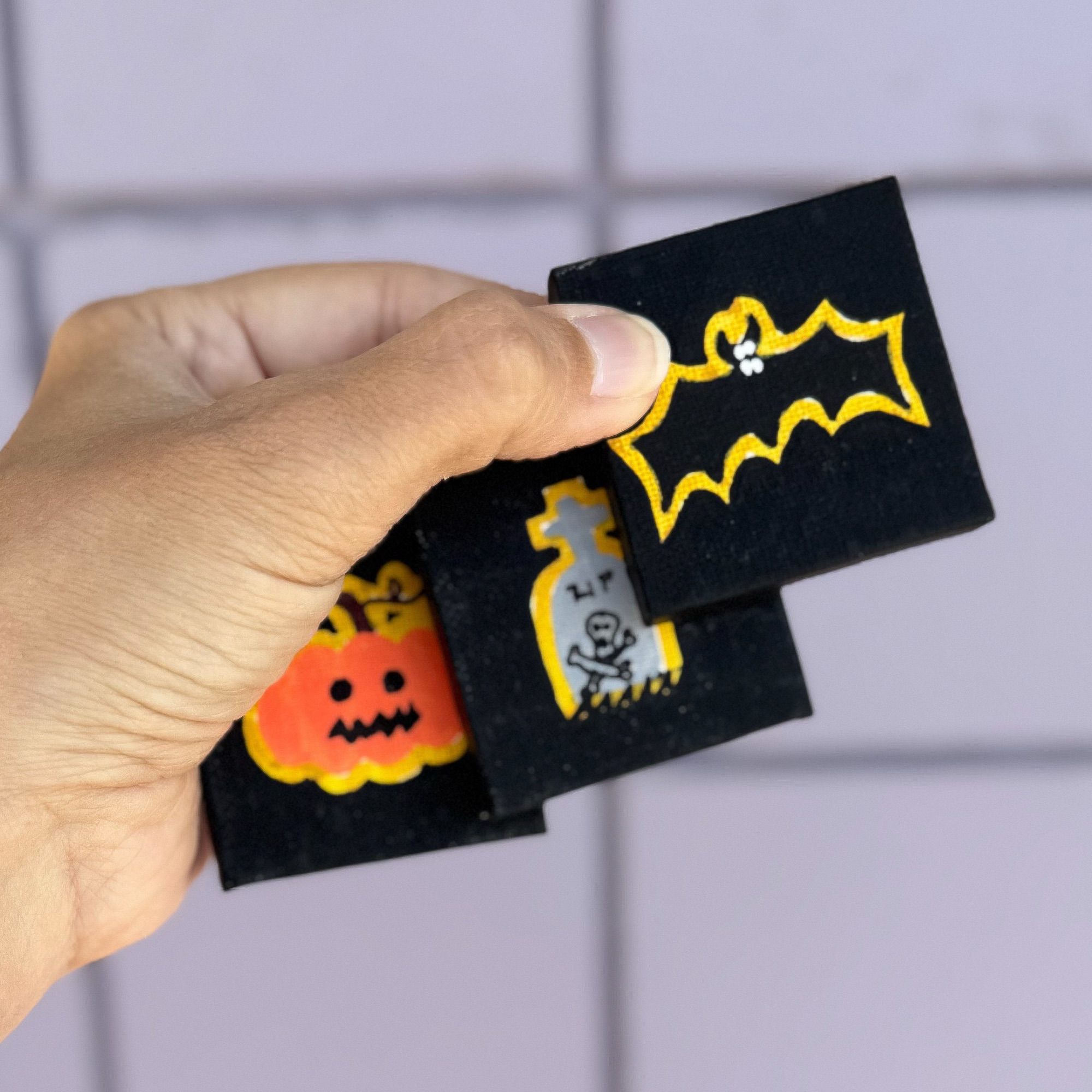 Tiny paintings of a bat, headstone and jack o lantern