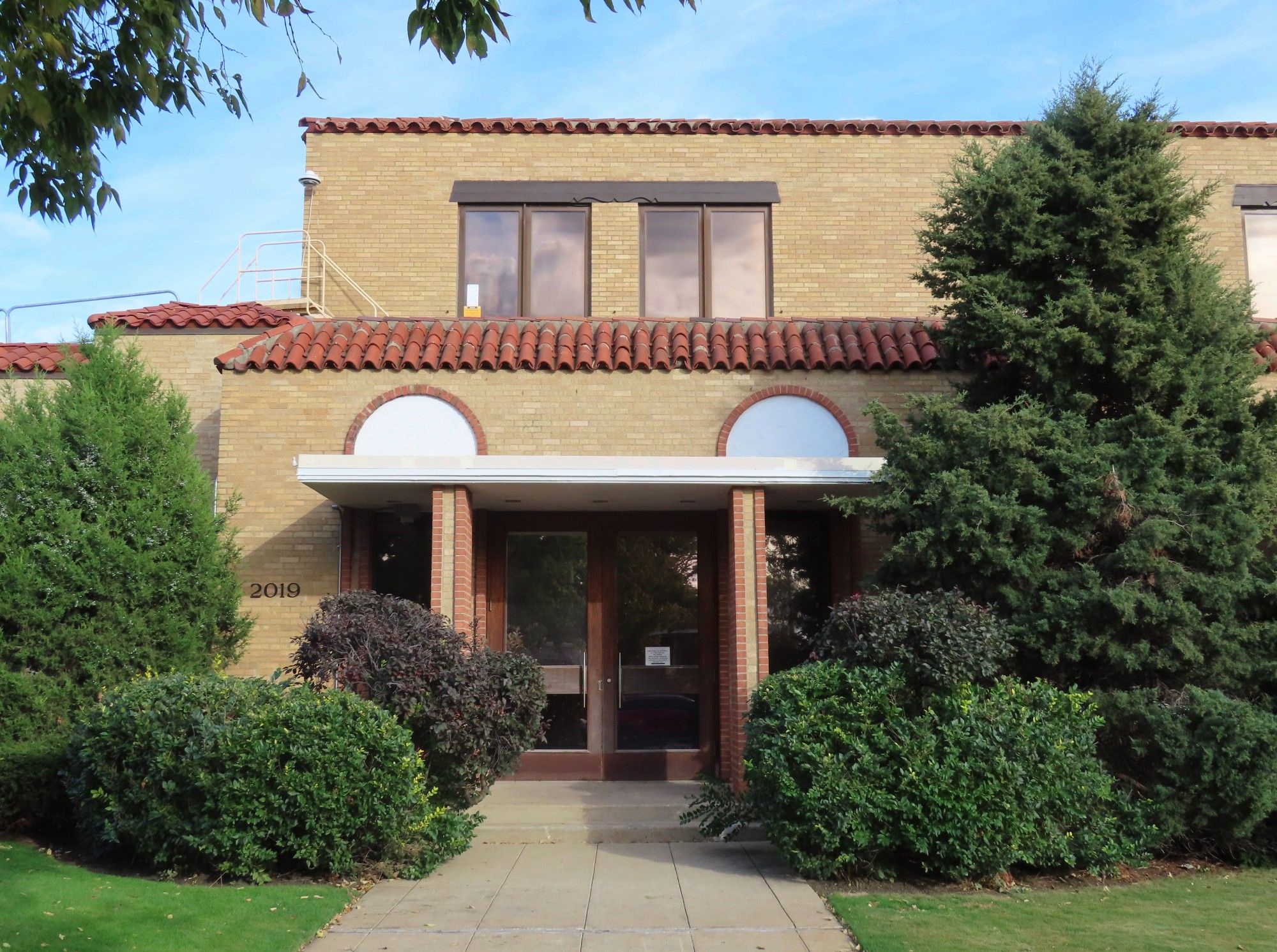 Color pic of more modern entrance, with same color brick and red clay roof tiles.