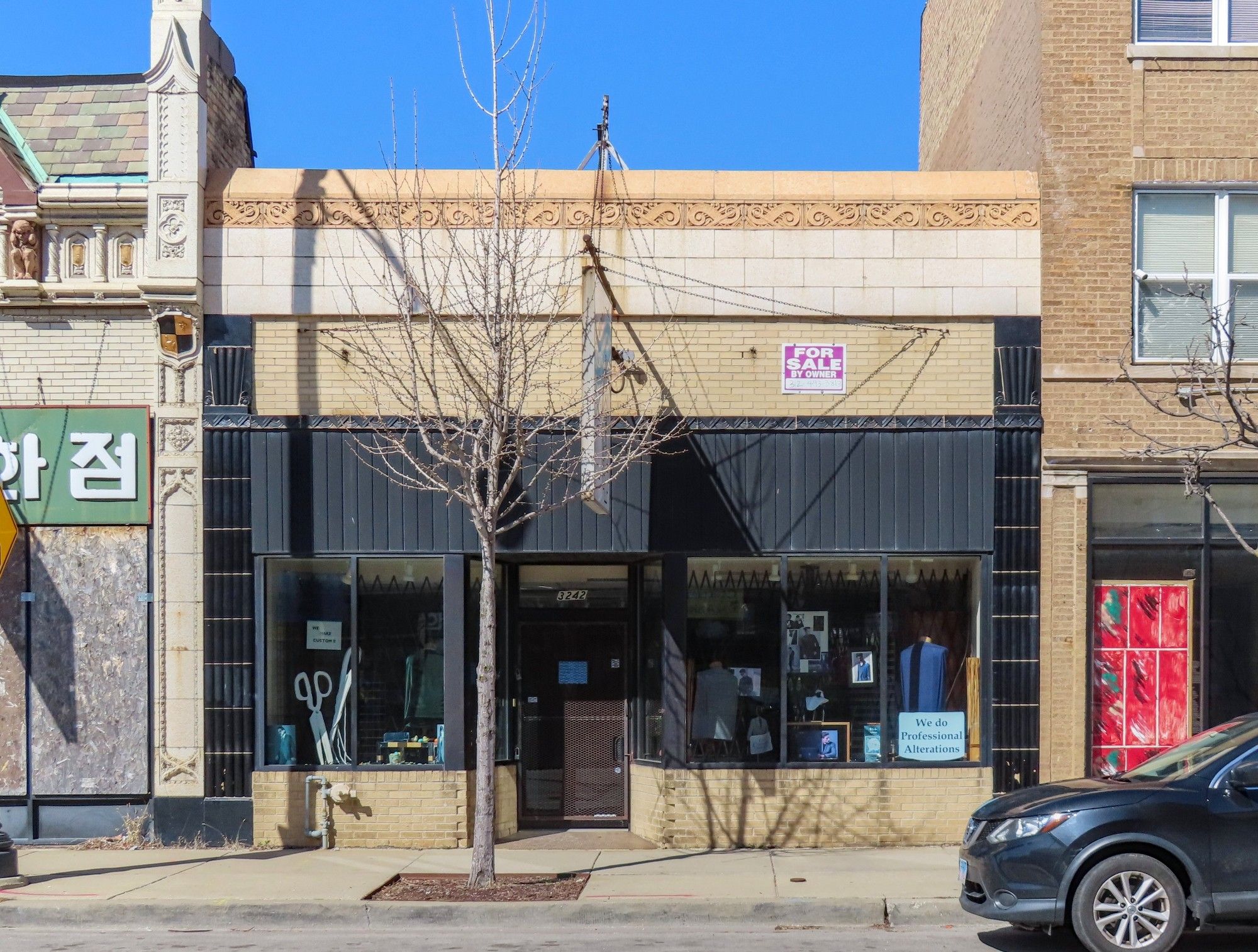 One-story store building in yellow brick, with black terra cotta pilasters on edges and wavy Deco pattern on parapet.