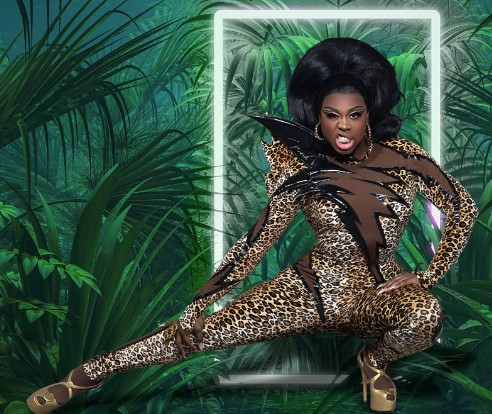 Drag queen wearing a leopard skin bodysuit with a lightning motif in front of a jungle-themed backdrop. Very fierce!