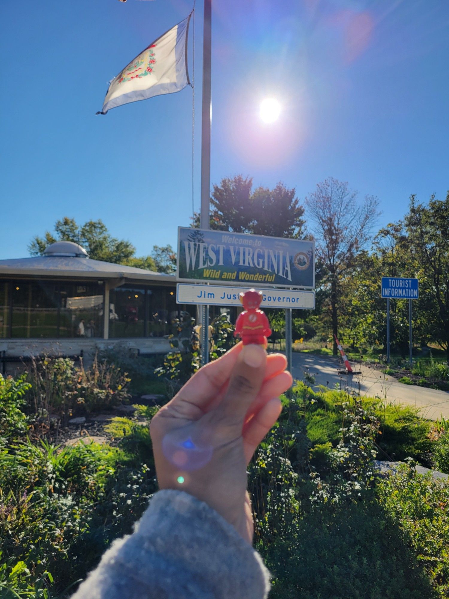 Lego Flash, a Lego mini figure of the superhero The Flash, in front of a sign that says welcome to West Virginia