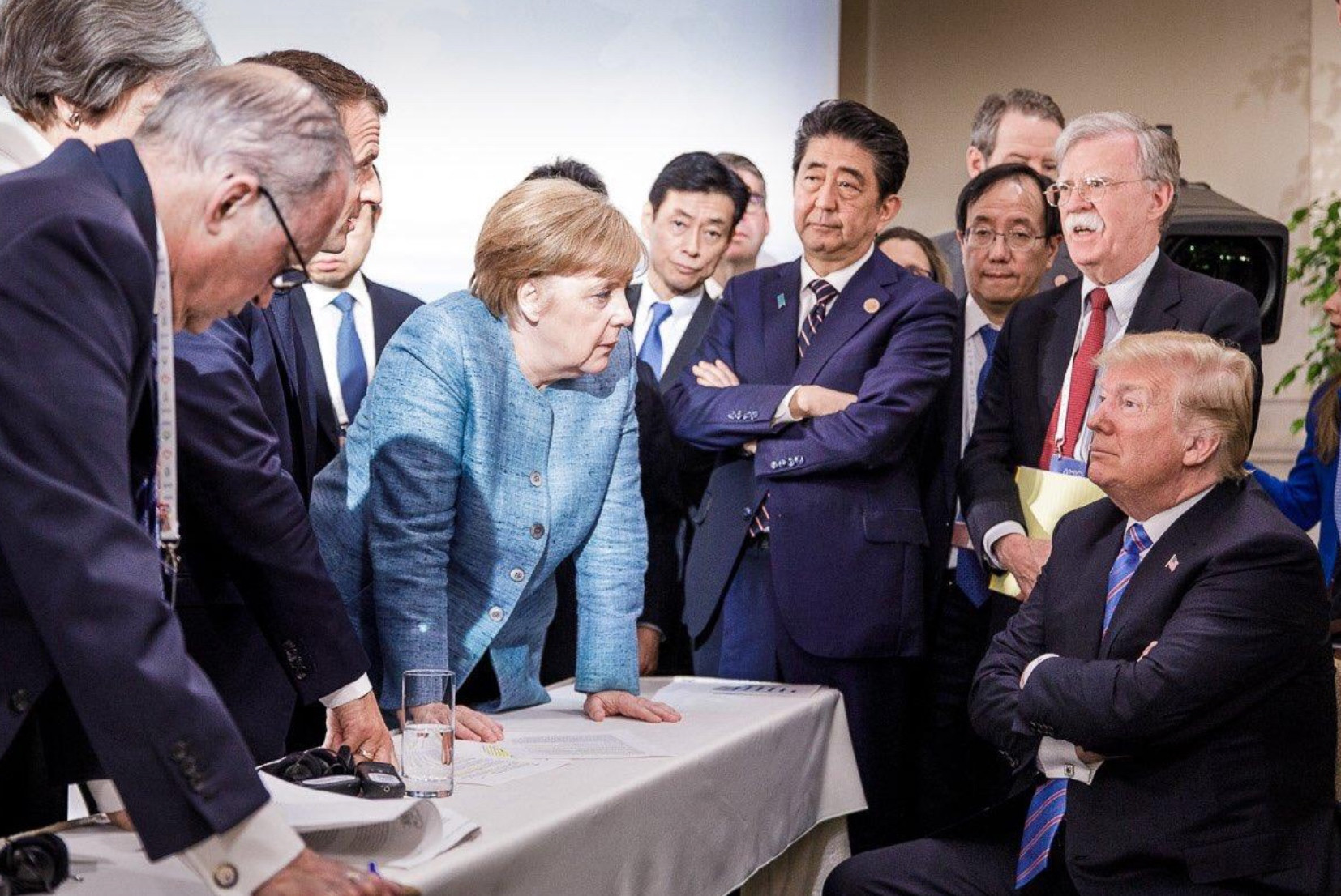 G7 leaders, Angela Merkel at the front, leaning in to persuade Donald Trump of something. 

He's sitting there with his arms crossed, looking like a stubborn toddler 