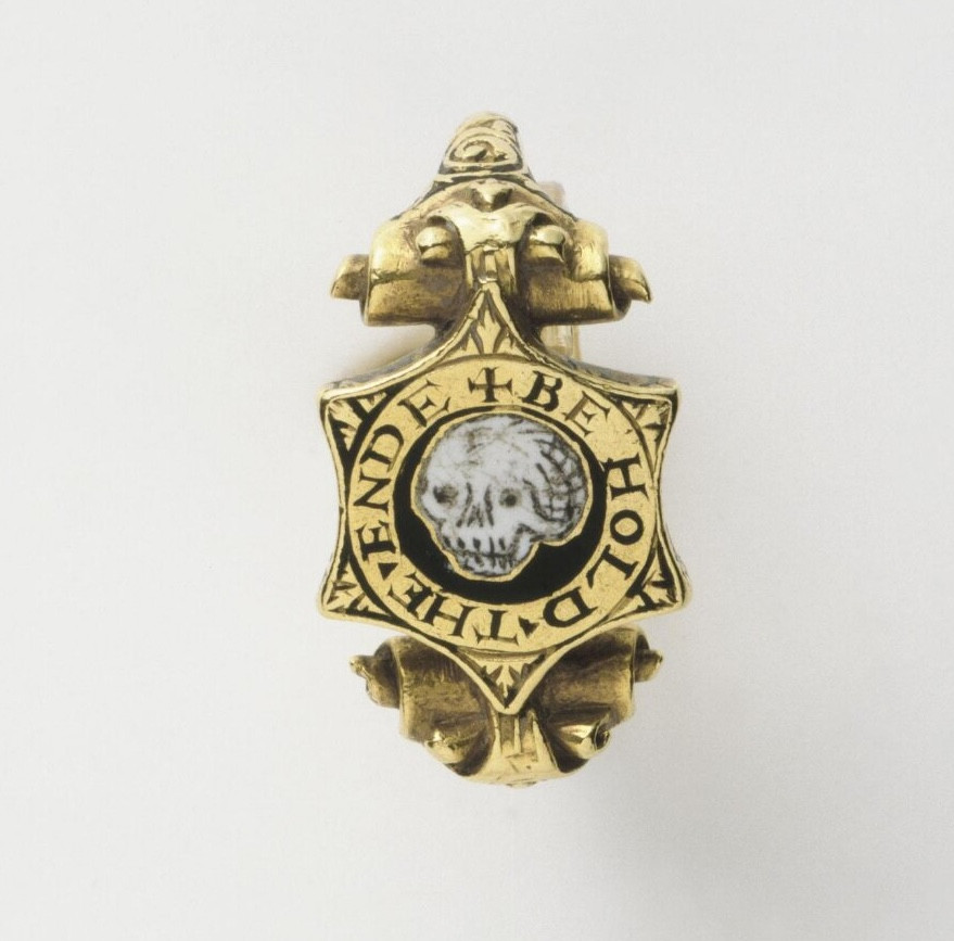 A pretty gold ring with a six pointed bezel featuring a black and white enamel skull within a gold circle engraved BE HOLD THE ENDE. Can't see it in the photo, but there's another inscription RATHER DEATH THAN FALS FAYTH and the initials M and L entwined in a lover's knot.