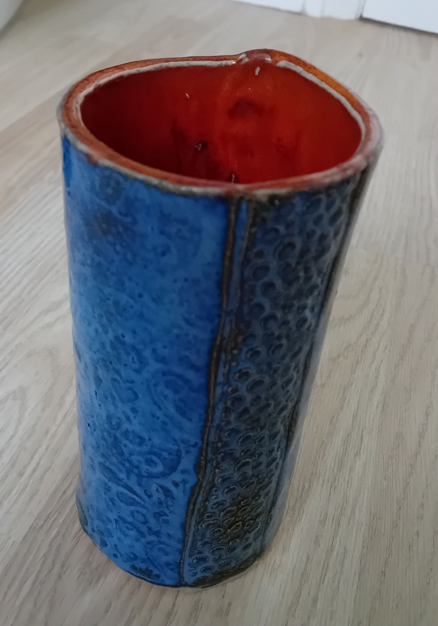 Bright blue glazed cylindrical textured vase, with bright orange interior.