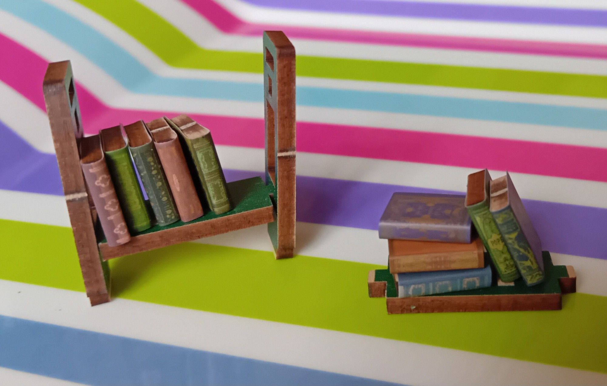 A close-up of 10 more tiny books on a partially constructed bookshelf