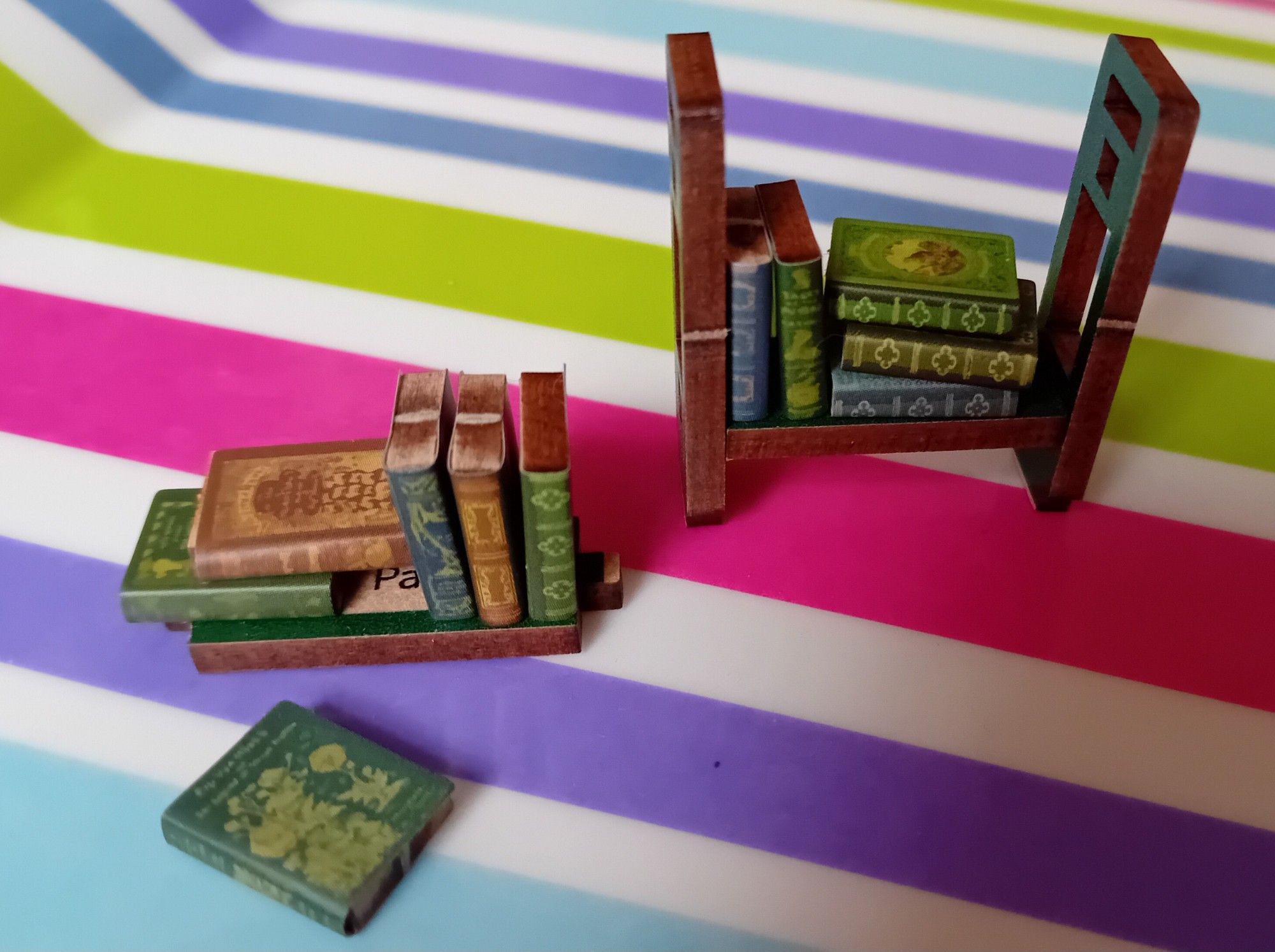 A close-up of 11 tiny books and a half constructed bookshelf