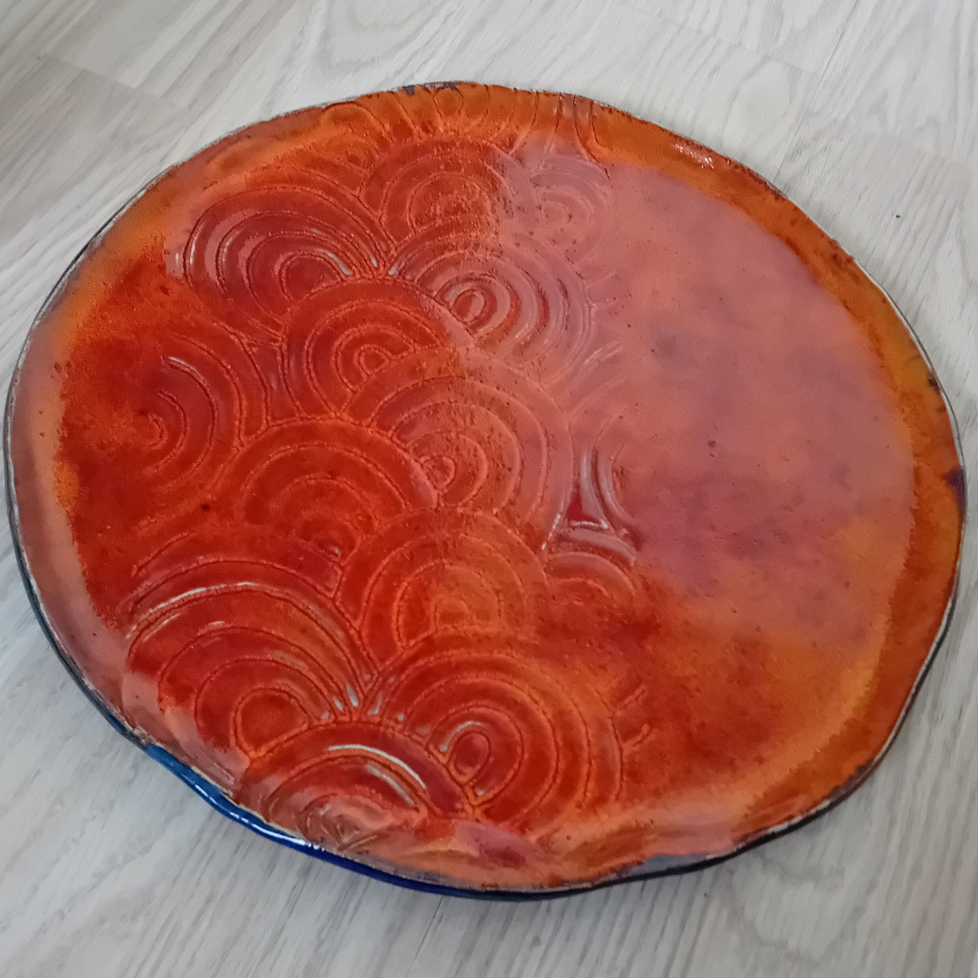 Bright orange circular cheese platter, with swirly texture on one side