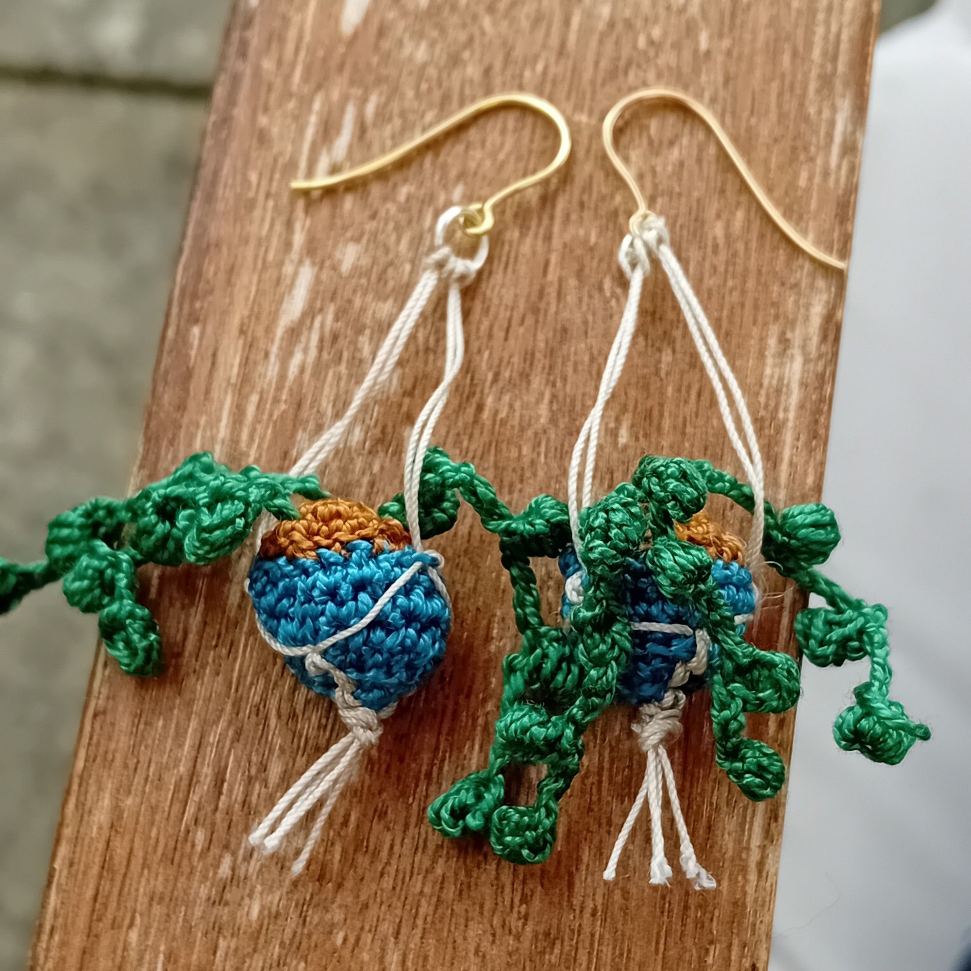 A pair of tiny crochet hanging plant earrings