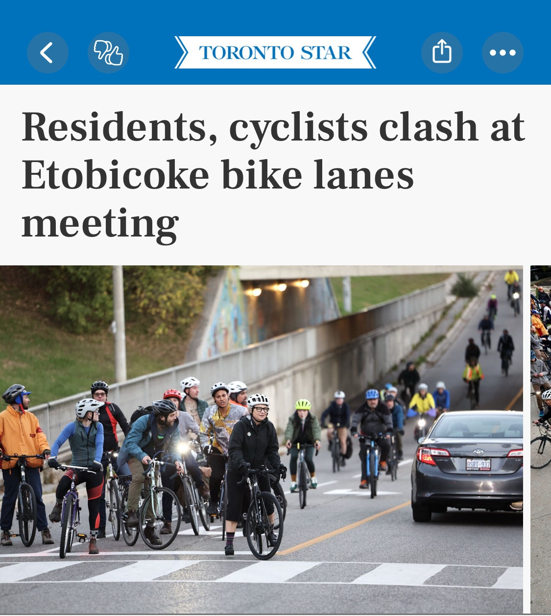 A Toronto Star headline reads “Residents, cyclists clash at Etobicoke bike lanes meeting”. Below is a photo of maybe 20 cyclists waiting to turn left from the middle lane at an intersection while several more roll up behind them. 