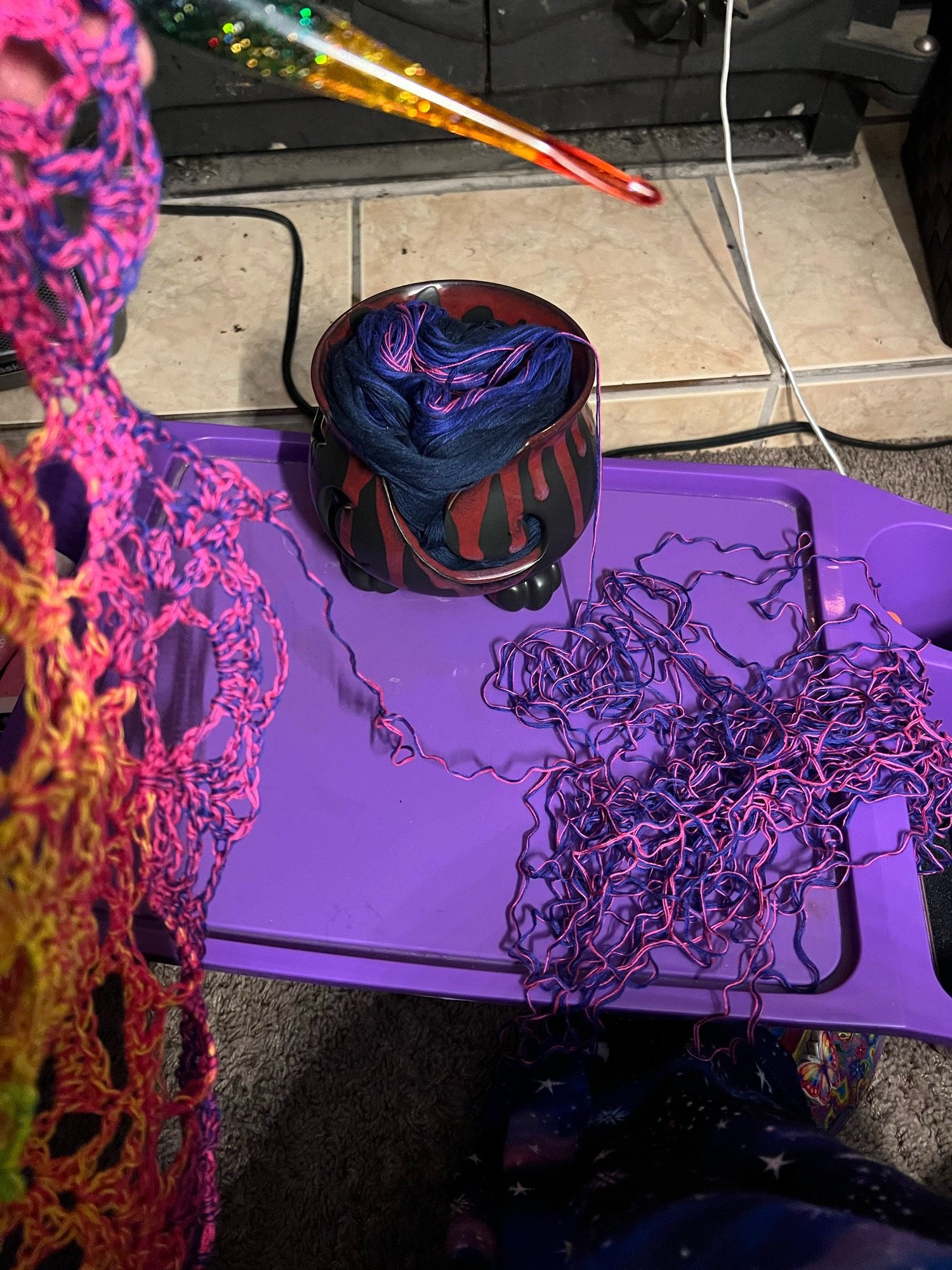 A pile of crinkled yarn all in pulled out from a shawl, sitting sadly on a purple tray.