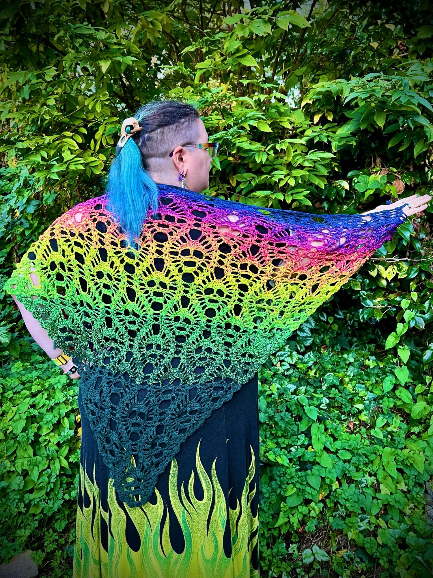 A crocheted shawl with a repeating skull pattern in fluorescent colors