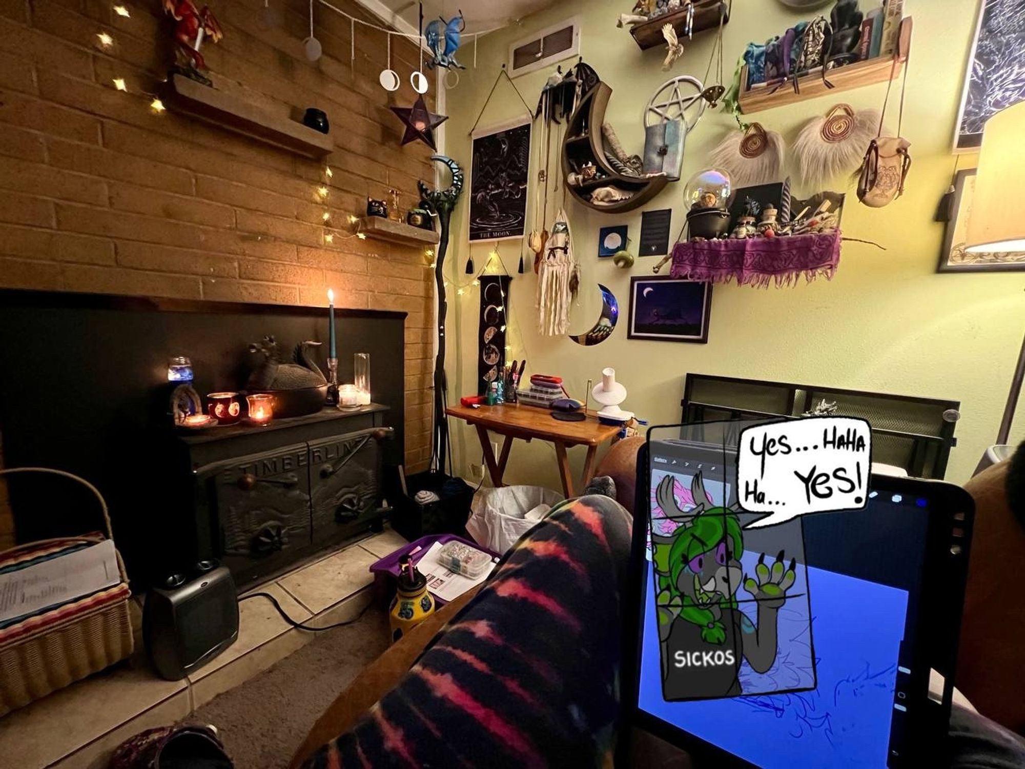 A cozy corner in a home, with candles and various witchcraft implements,, many of them are moon themed. The photographer has an iPad between her knees, the screen is obscured by a dragon sticker.