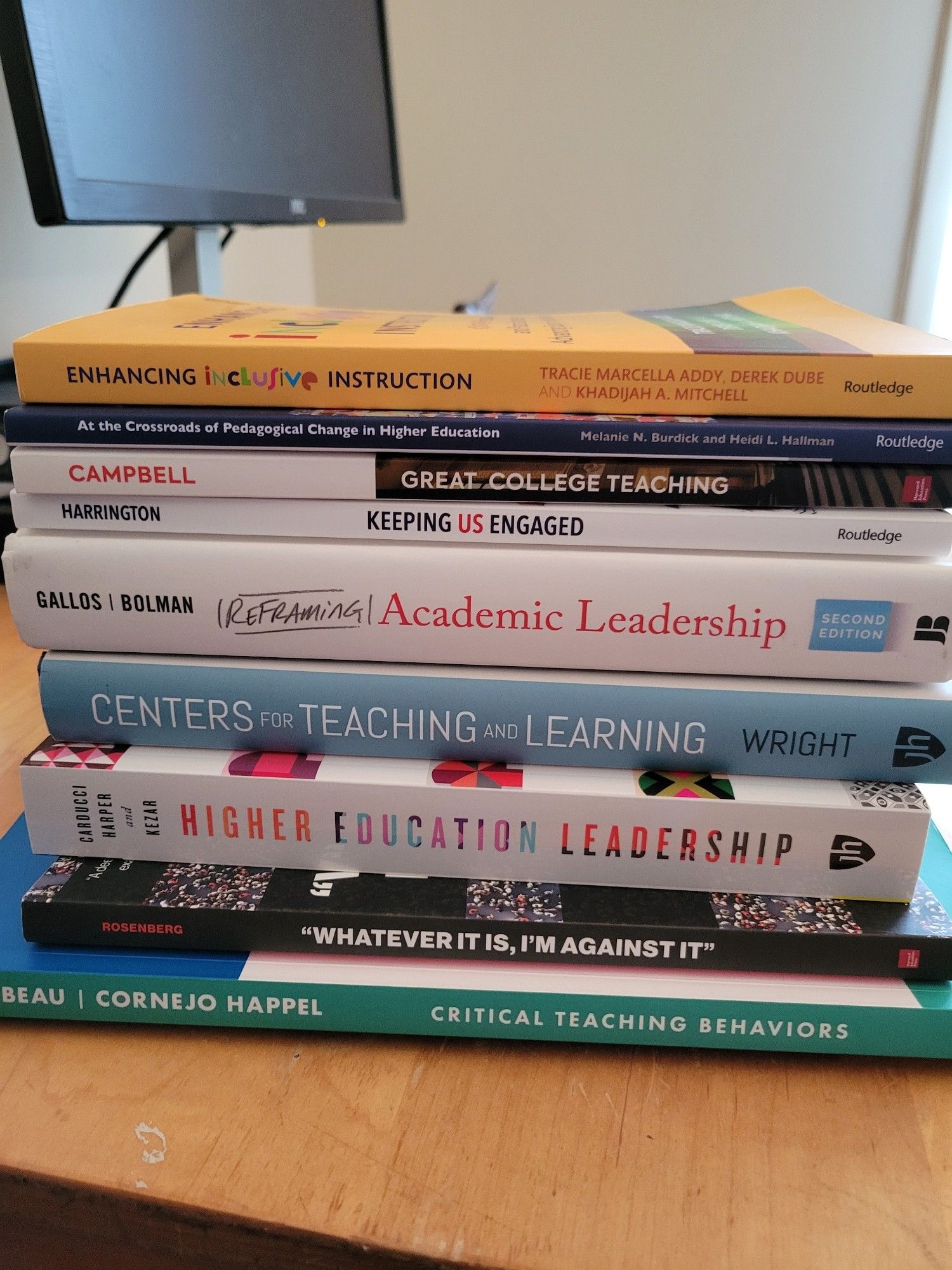 Stack of books about teaching, learning and academic leadership. Includes Enhancing Inclusive Education by Tracie Marcella Addy; Critical Teaching Behaviors by Barbeau and Cornjo Happel; Centers for Teaching and Learning by Mary Wright; Whatever is Is I'm Against It by Rosenberg.