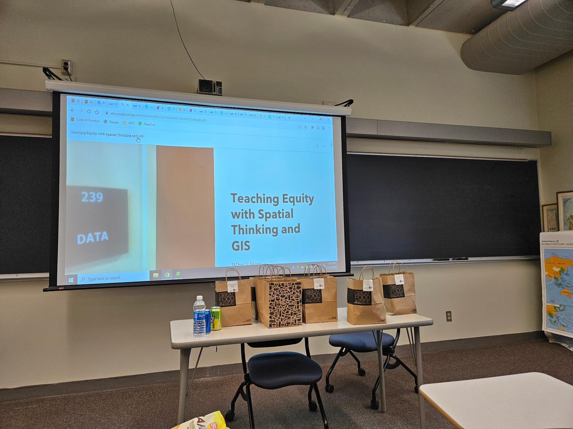 Front of classroom. Text on projected screen says "teaching equity with spatial thinking and GIS"