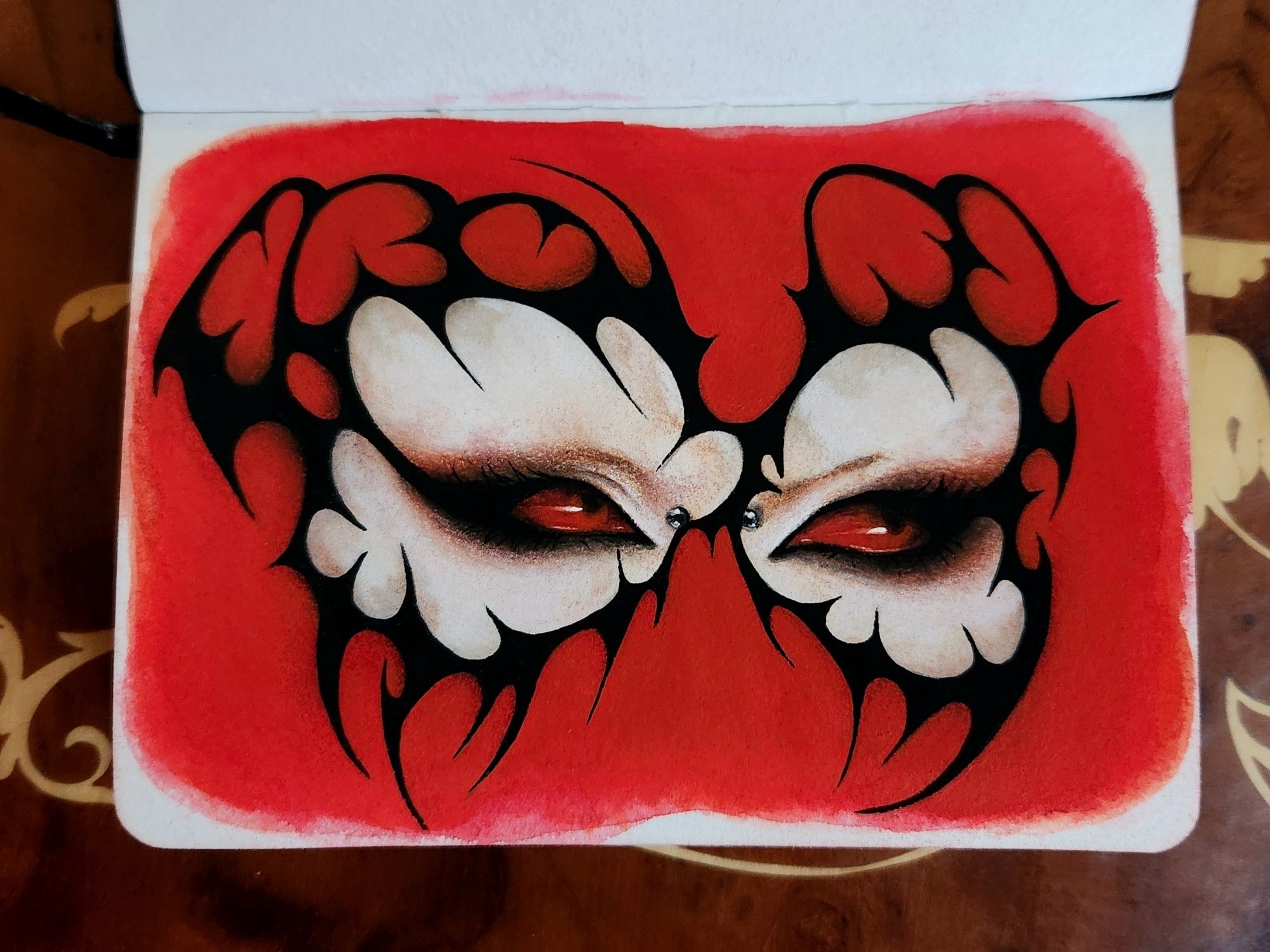 Painting of a person's completely red eyes framed in graphic black liner. It surrounds their eyes like a mask and contains many thorny points. The background is painted with the same red as their eyes. Made with watercolor, gouache, and colored pencils