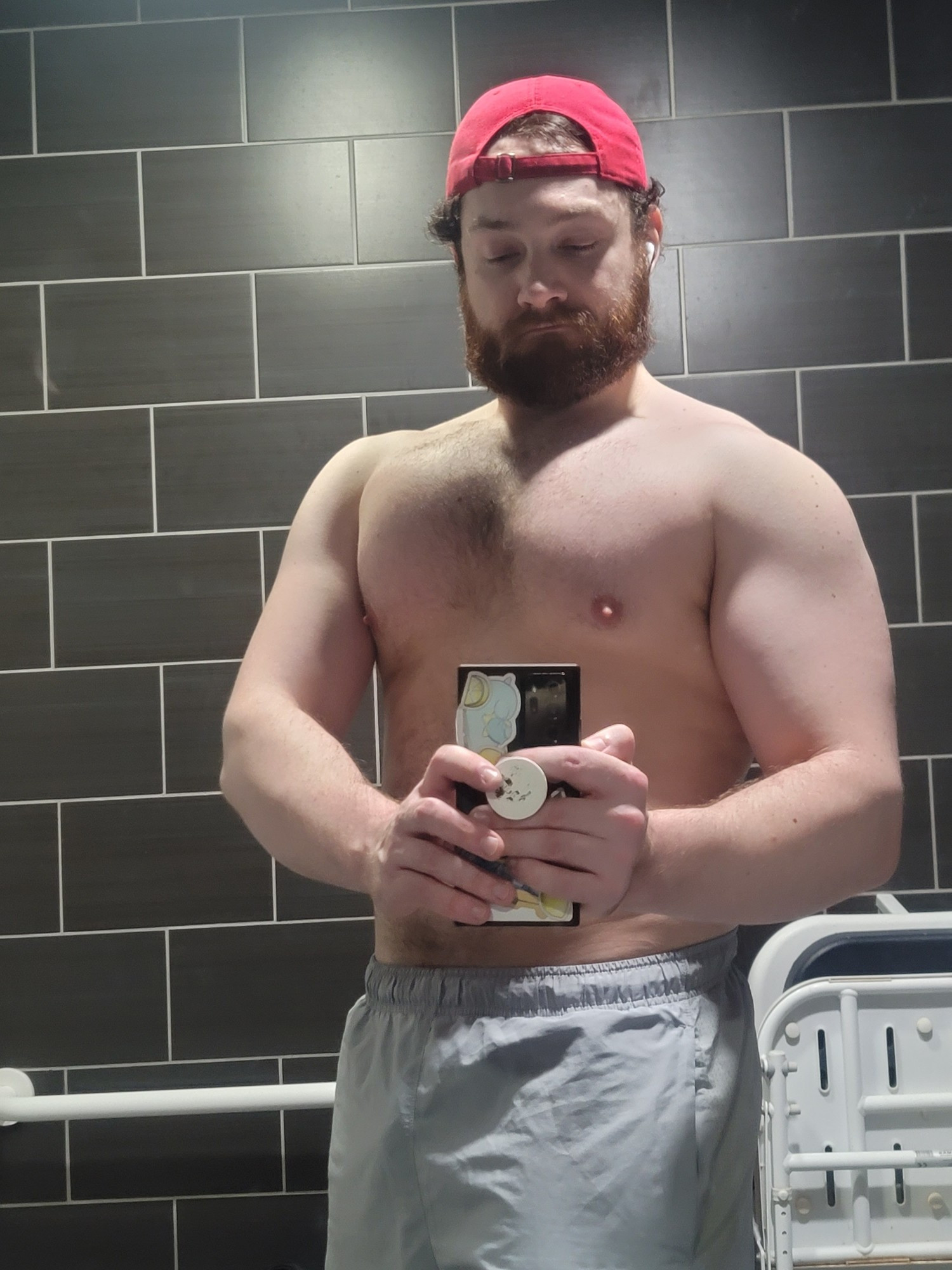 Me shirtless in a red cap, flexing my muscles