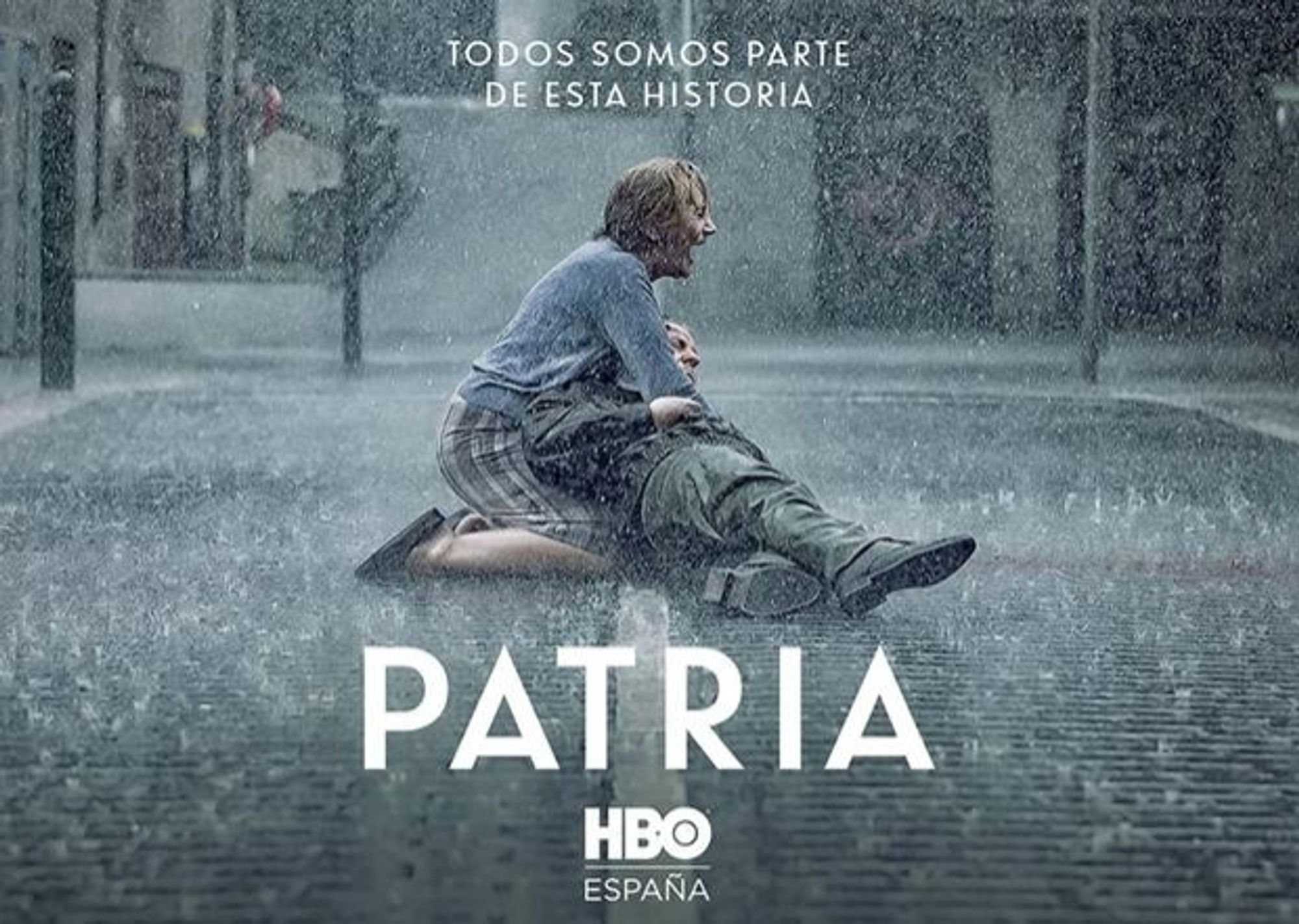 Cartel de la serie Patria.
Se ve a un hombre tirado en el suelo bajo la lluvia y a una mujer sujetándolo en sus brazos y llorando. Y se puede leer: todos somos parte de esta historia.