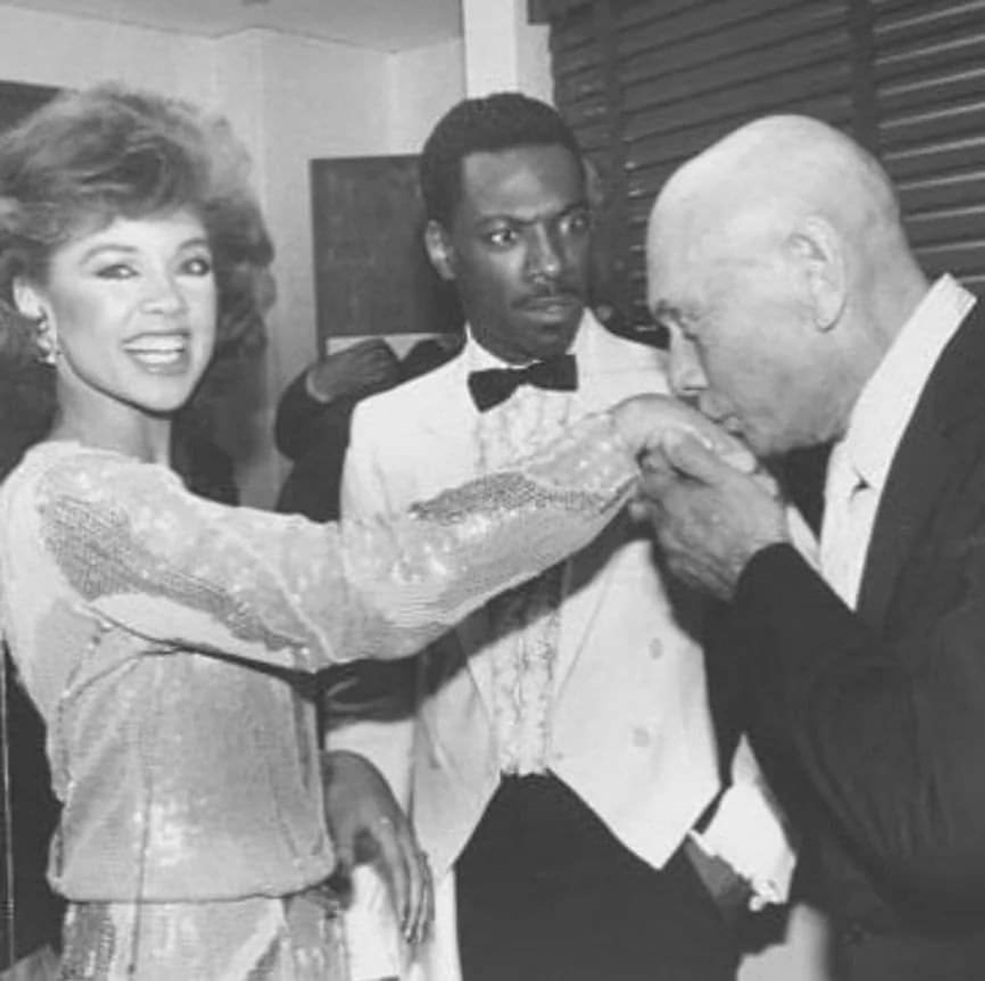 Yul Brynner kissing the hand of Vanessa Williams while Eddie Murphy is beside himself.