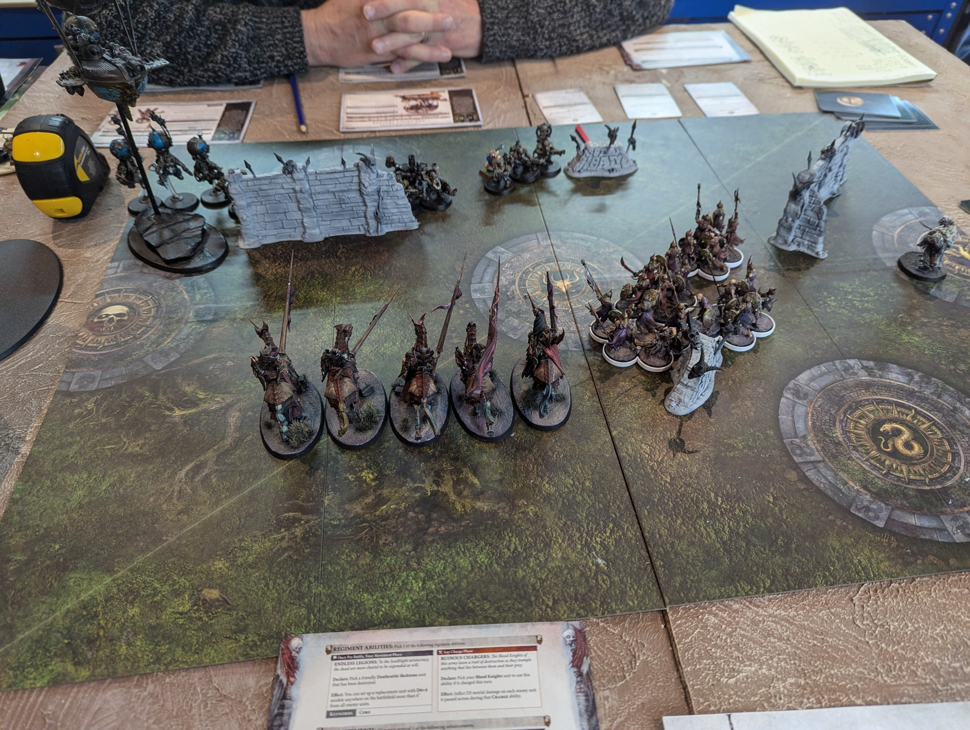 Picture shows a tabletop wargame in play. One army covers most of the middle of the board while the other is hidden away in a corner.