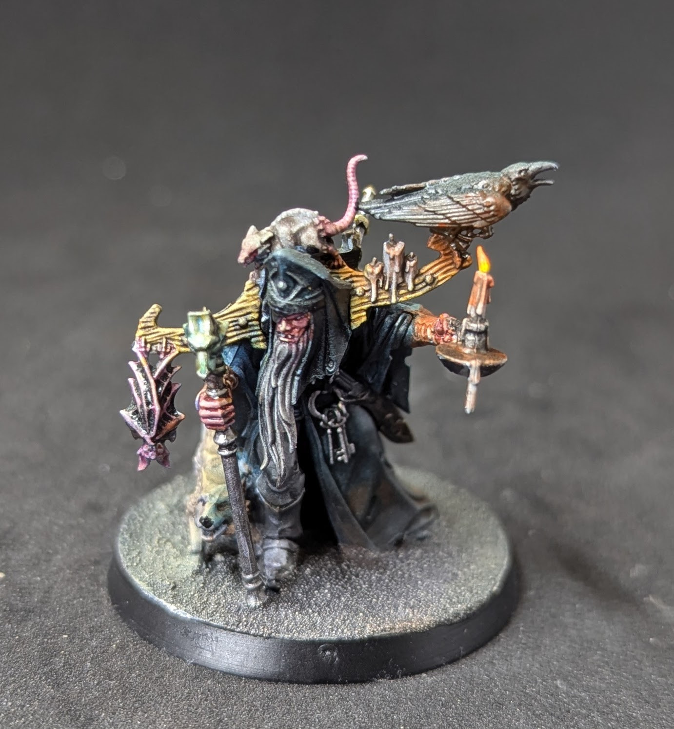 A photo of a Torgilius miniature figure from Games Workshop's Age of Sigmar range. He's a hunched over wizard with a candle and several critters crawling on him.