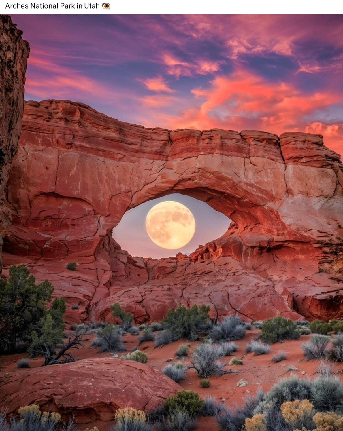Arches national park, a full moon shines through the opening of red rock like the iris of an eye.