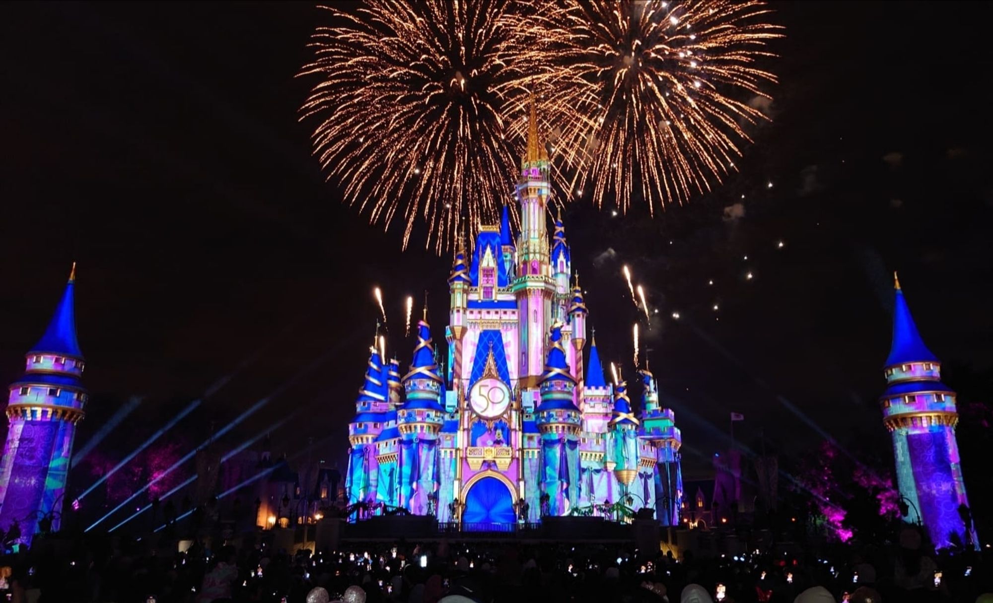 Cinderella Castle at Walt Disney World at night lit up for Enchanted with fireworks in the night sky