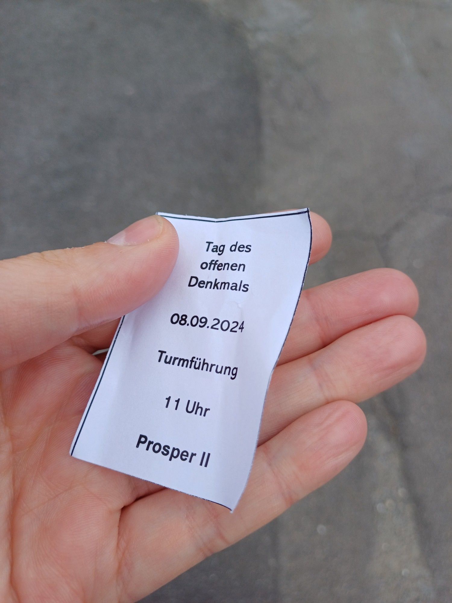 Ein Zettel in der Hand mit Ticket zur gruppenführung auf den Förderturm der Zeche Prosper 2