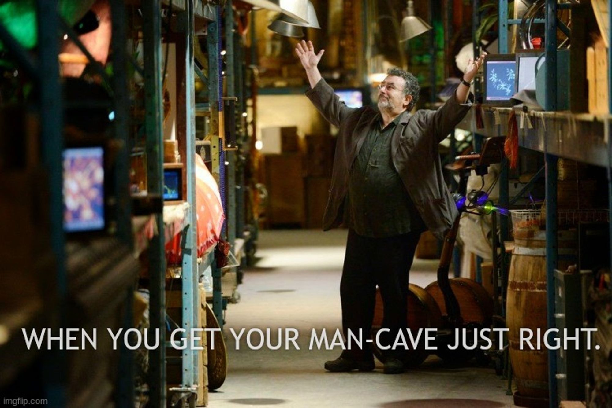 Artie from Warehouse 13 being happy in one of the Warehouse aisles. The caption is 'When you get your man-cave just right'.