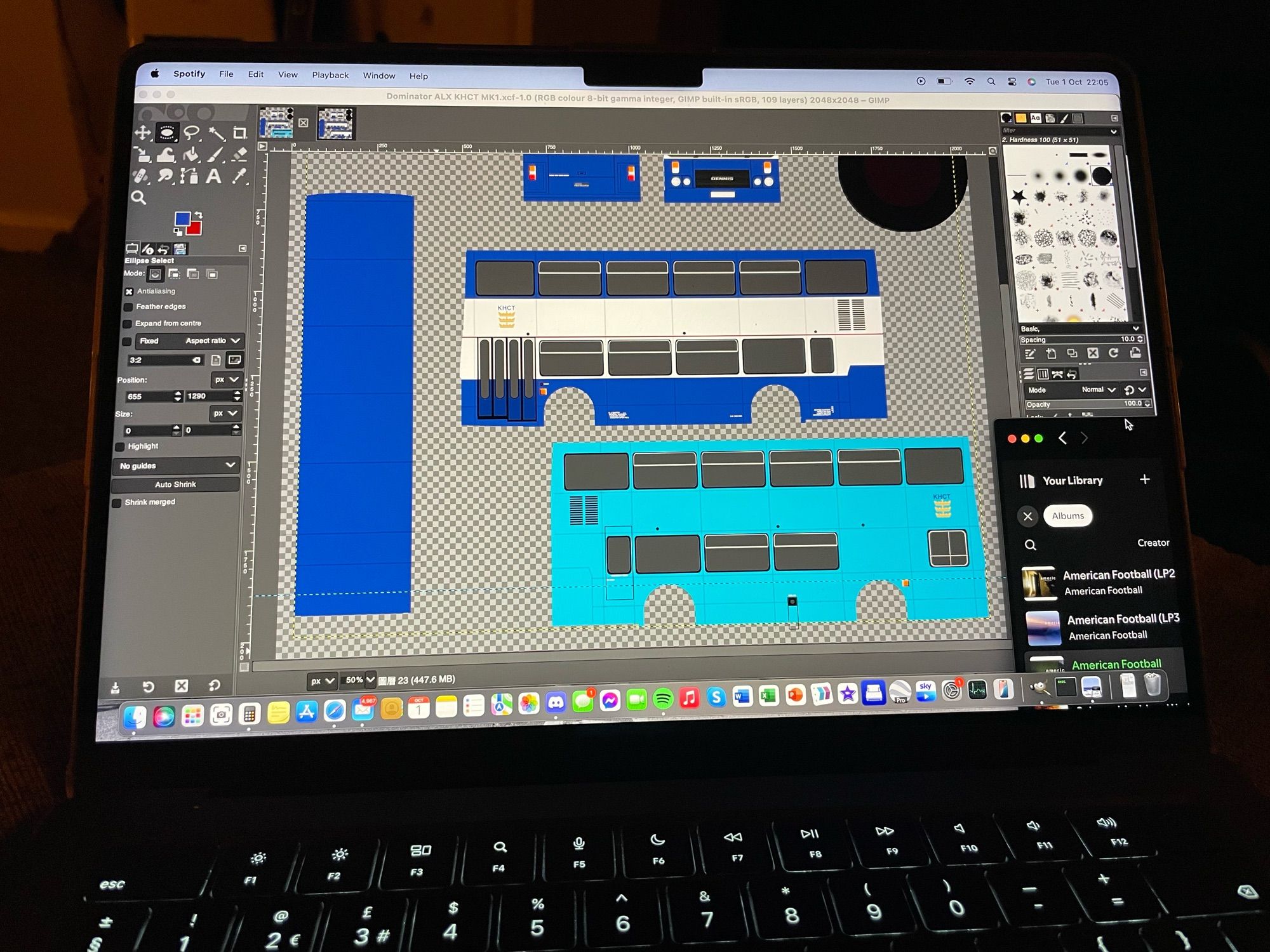 Photograph of a MacBook screen with the GIMP editing software open, editing a blue-and-white double-decker bus. Tucked into the far right is a Spotify tab with American Football's first self-titled EP playing.