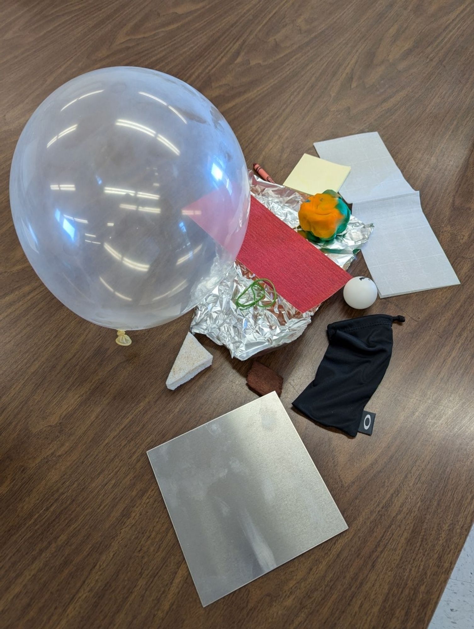 A pile of everyday objects with different physical properties, such as metal, balloon, sandpaper, playdough.