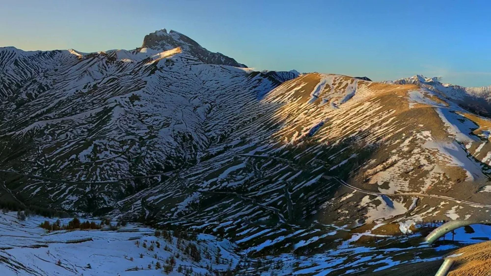 Le sommet de la Grande Séolane et les pentes du Col d'Allos, à moitié recouvertes de neige, au moment du soleil couchant.