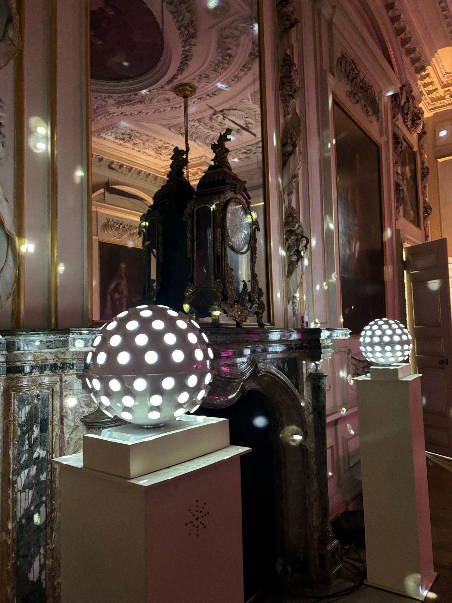 Disco balls by a grandfire place, clock and mirror