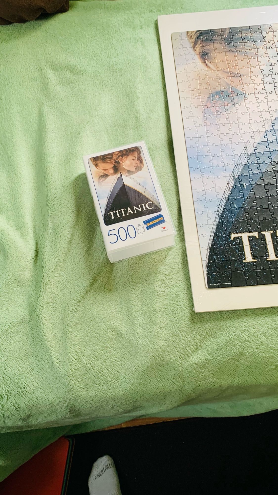 Plastic case of Blockbuster 500 pieces jigsaw puzzle beside jigsaw puzzle of titanic.