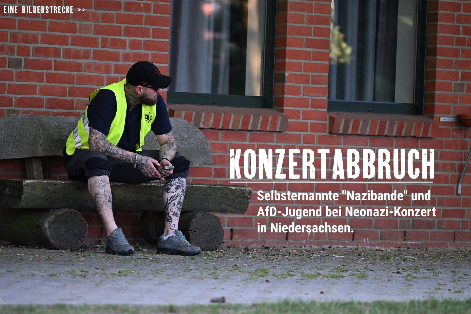 Ein Neonazi mit gelber Warnweste sitzt auf einer Holzbank und schaut von der Kamera weg.