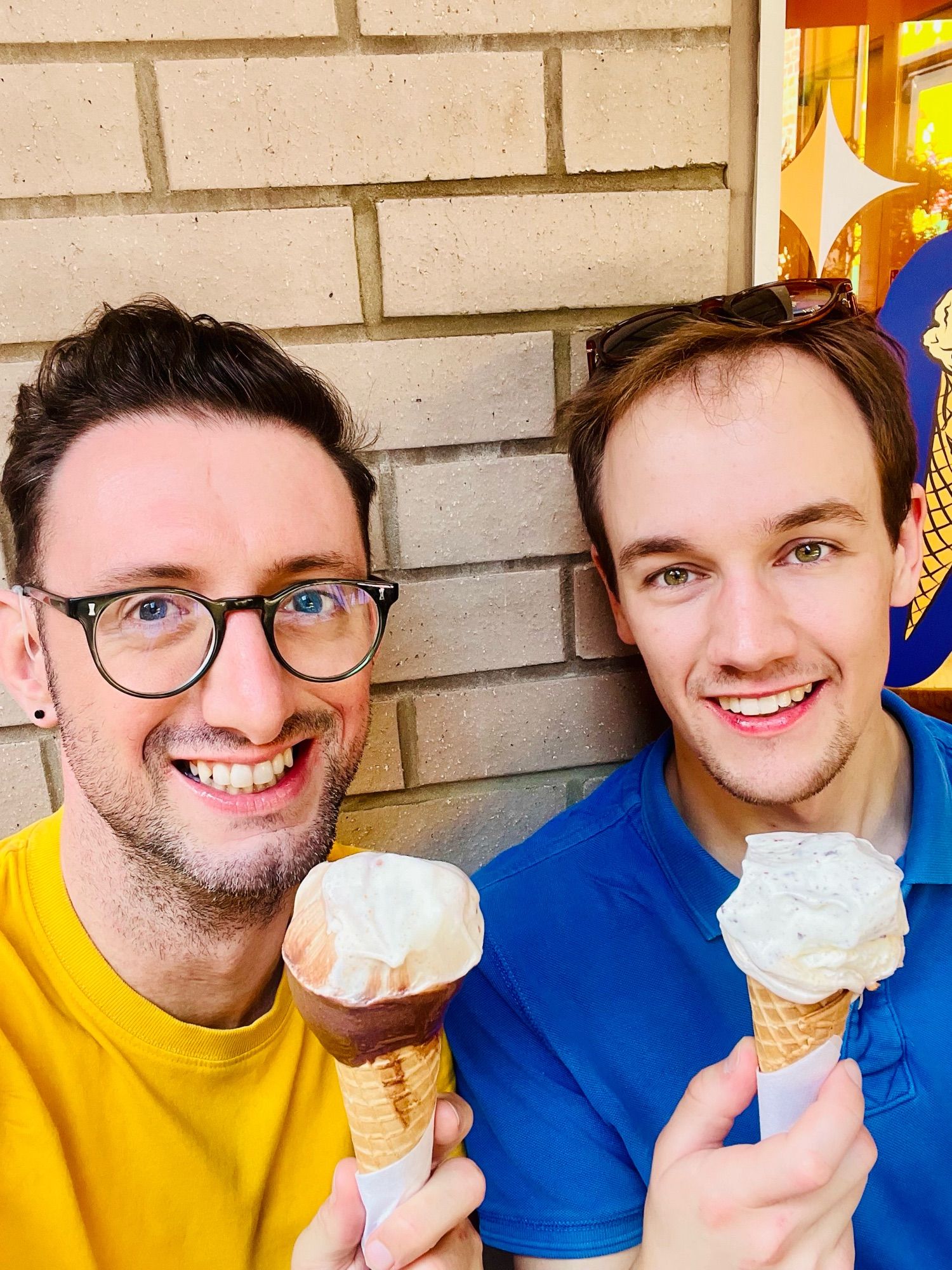 Jake in a yellow T-shirt and glasses. Jacob in a blue shirt. They smile at the camera and both hold ice creams.