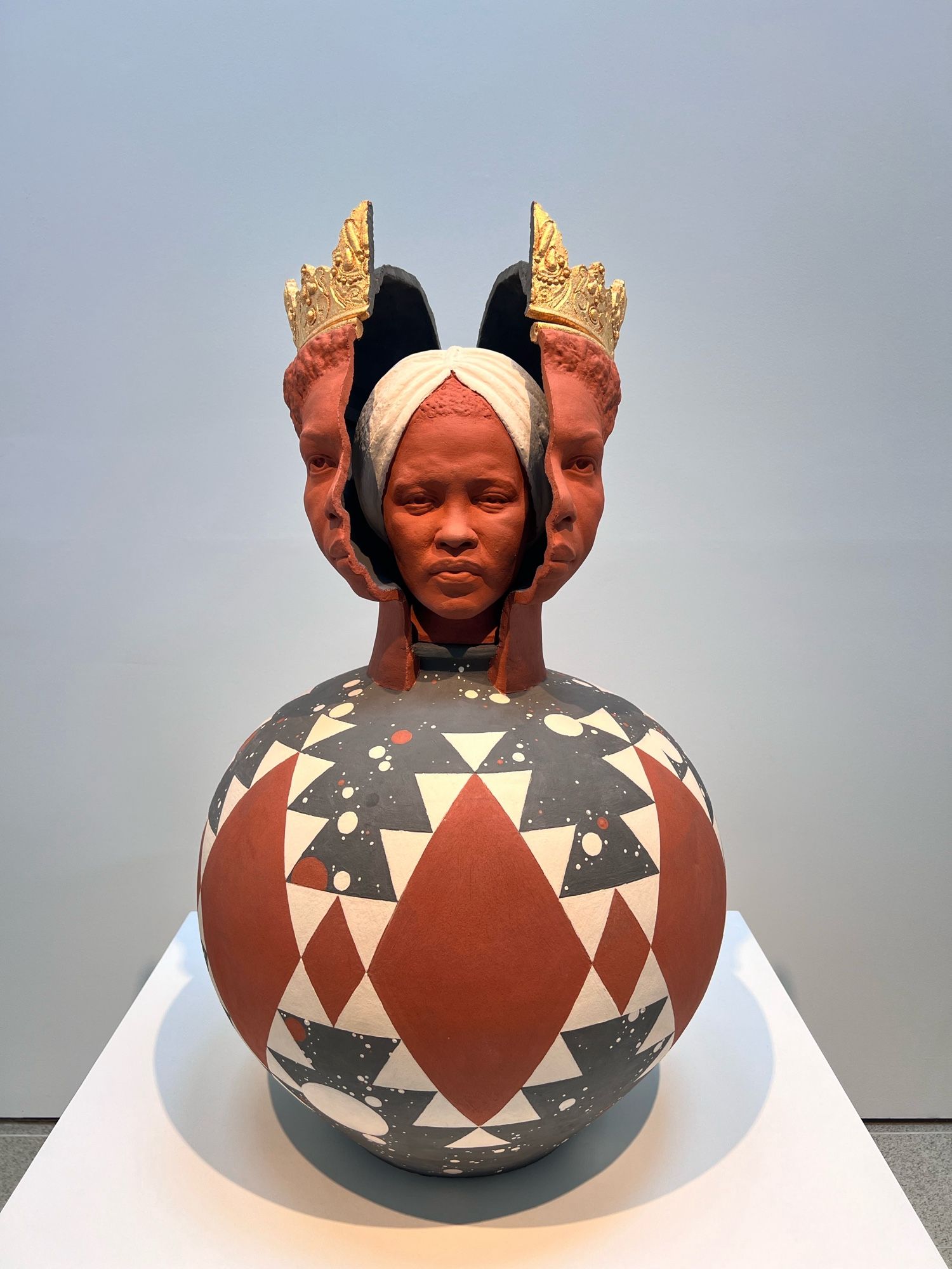 A sculpture of a pot with Nina Simone encased by a black queen. The pot stands on a plinth.