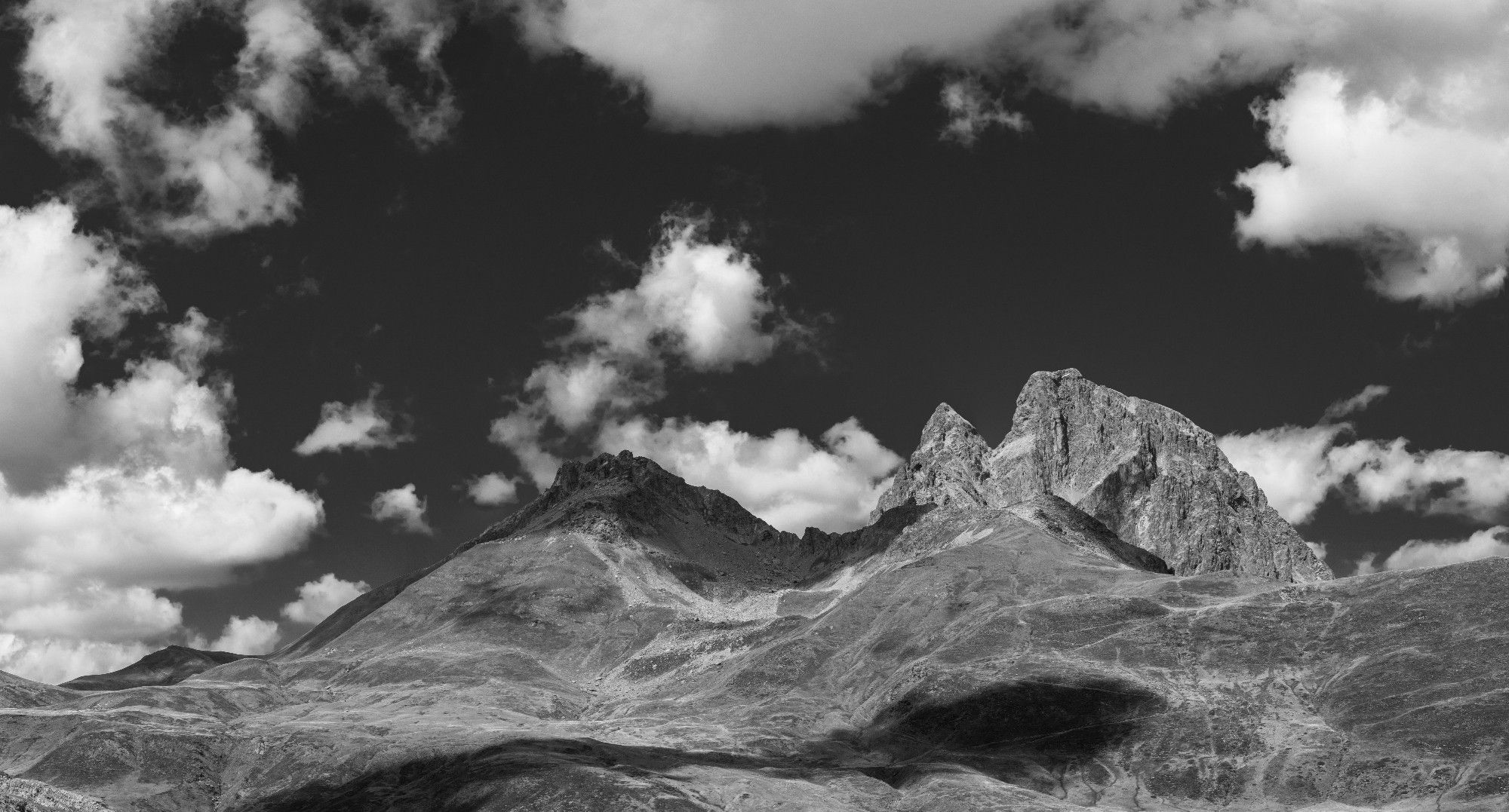 Fotografía en blanco y negro donde se ven los picos Peyreget y Midi D'Ossau son nieve y rodeados de nubes.