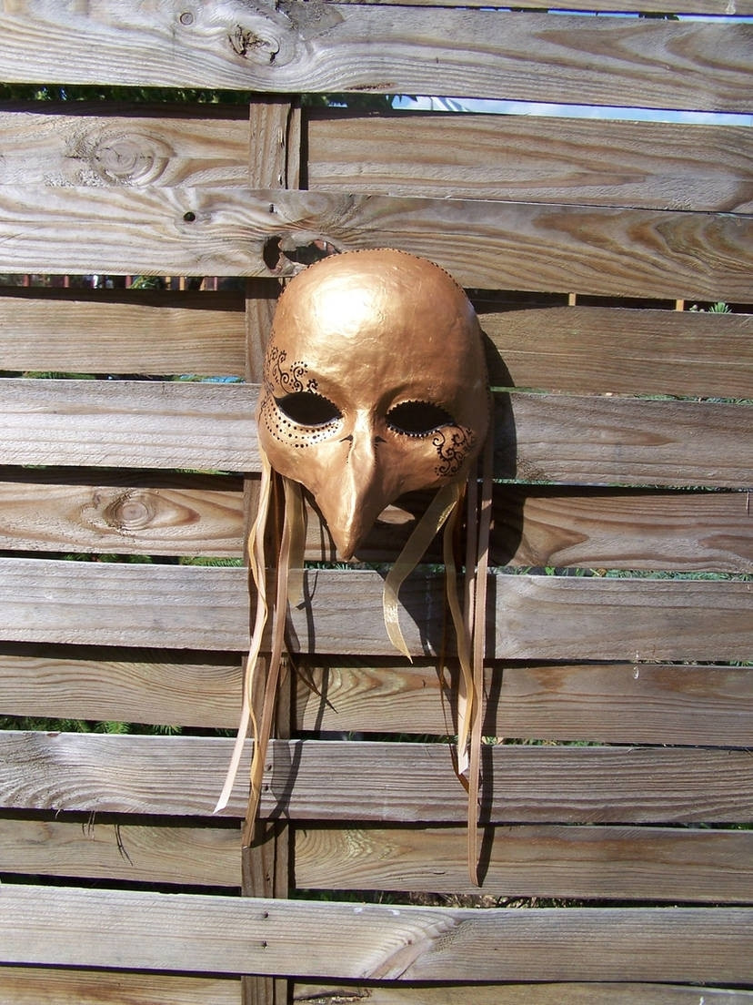 Paper mache fantasy mask of a bird, painted gold, with ribbons attached