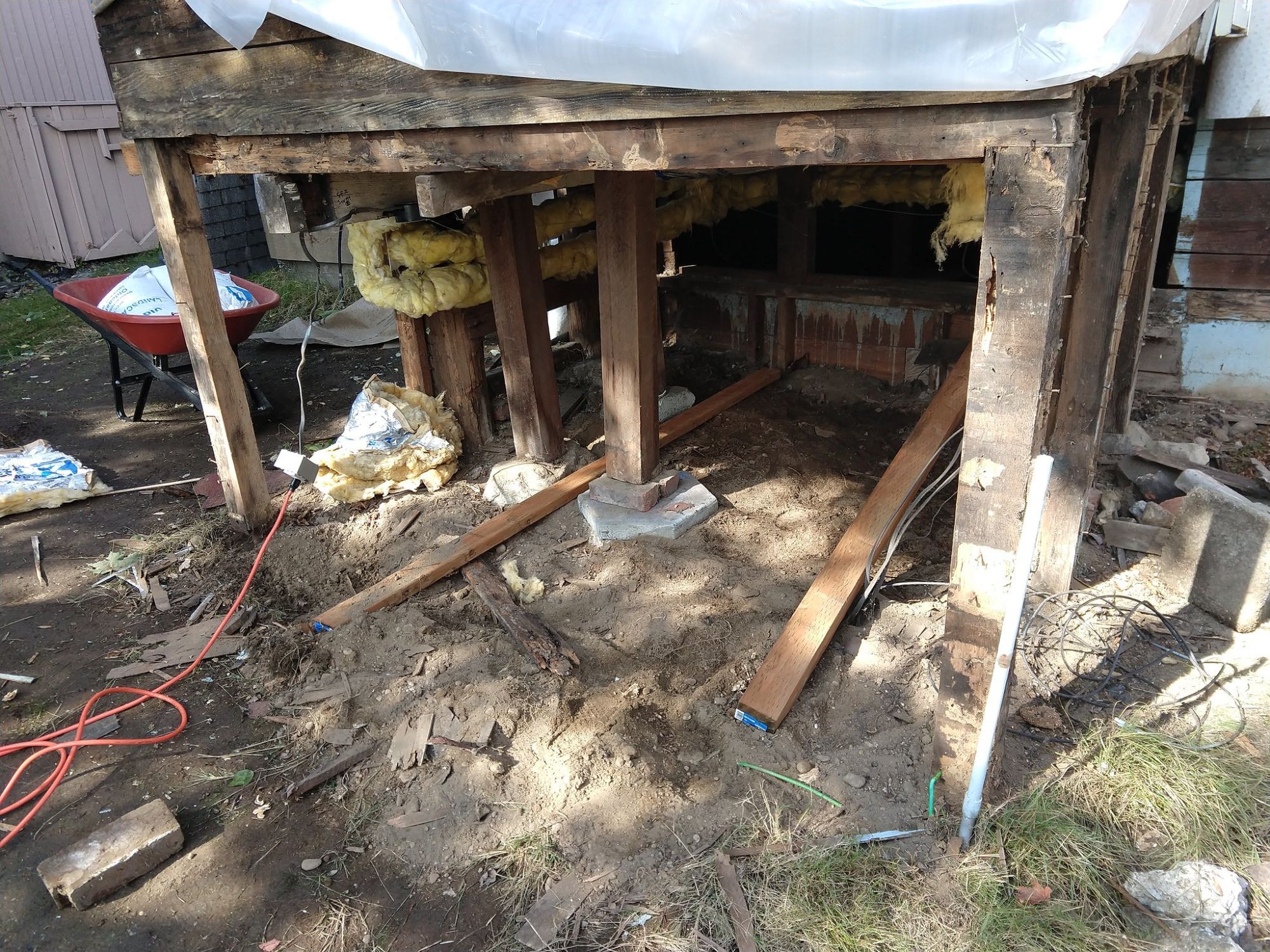 The support under a small building. There are several posts that simply land on top of large rocks or bricks on top of other rocks, and visible rot in several joists and supports. You, too, would be horrified to discover this was what was holding up your laundry room.