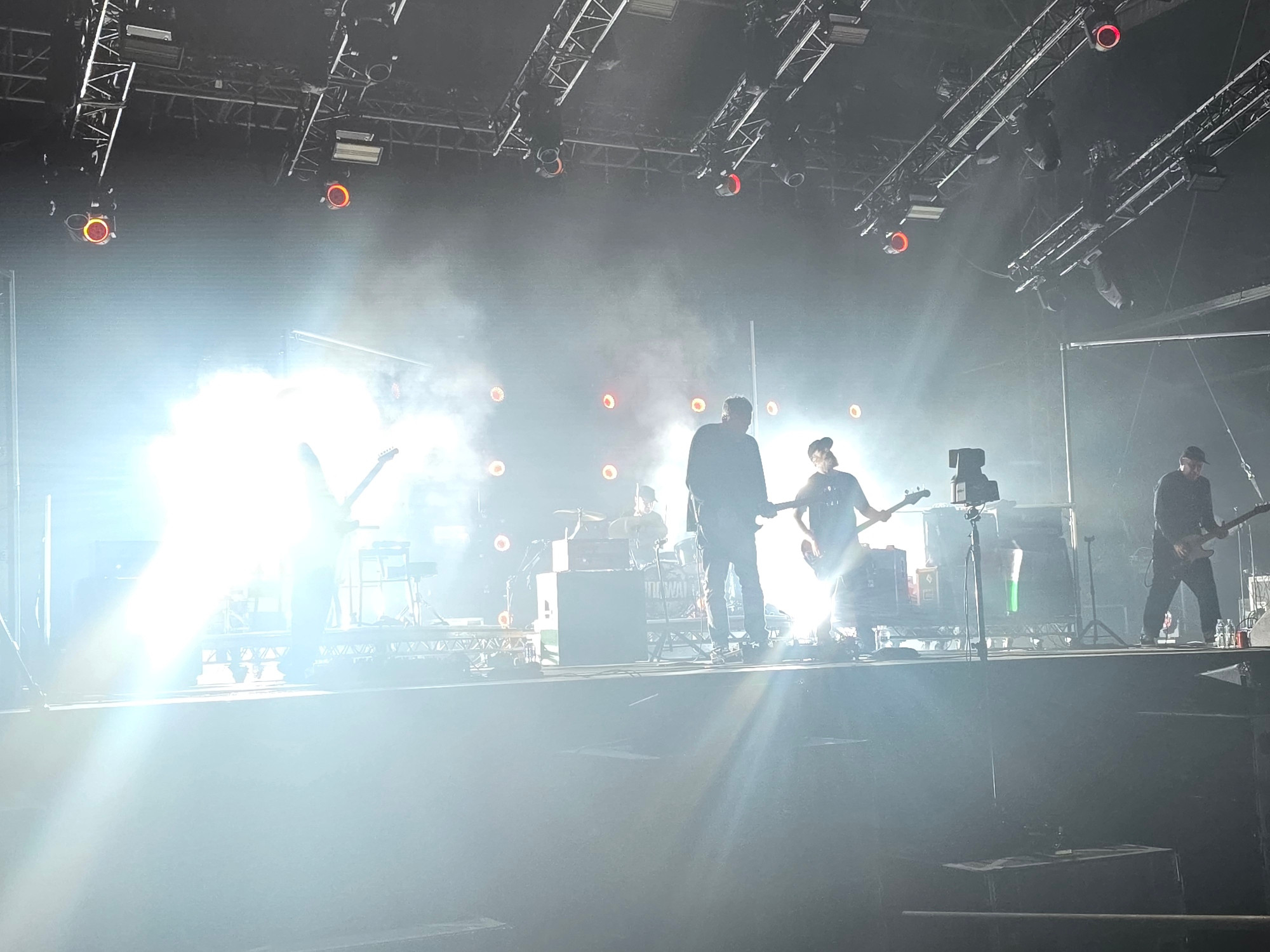 Bright lights on a stage, some vague figures with instruments are visible. 