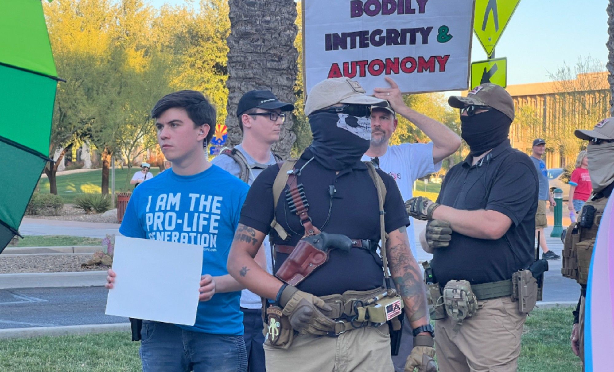 Anthony DeWitt wearing a blue I AM THE PRO LIFE GENERATION shirt alongside some armed militia guys in full skull masks at the Arizona State Capitol countering Roe v. Wade protests 

People surrounding the group can be seen holding up pro-choice signs and rainbow umbrellas