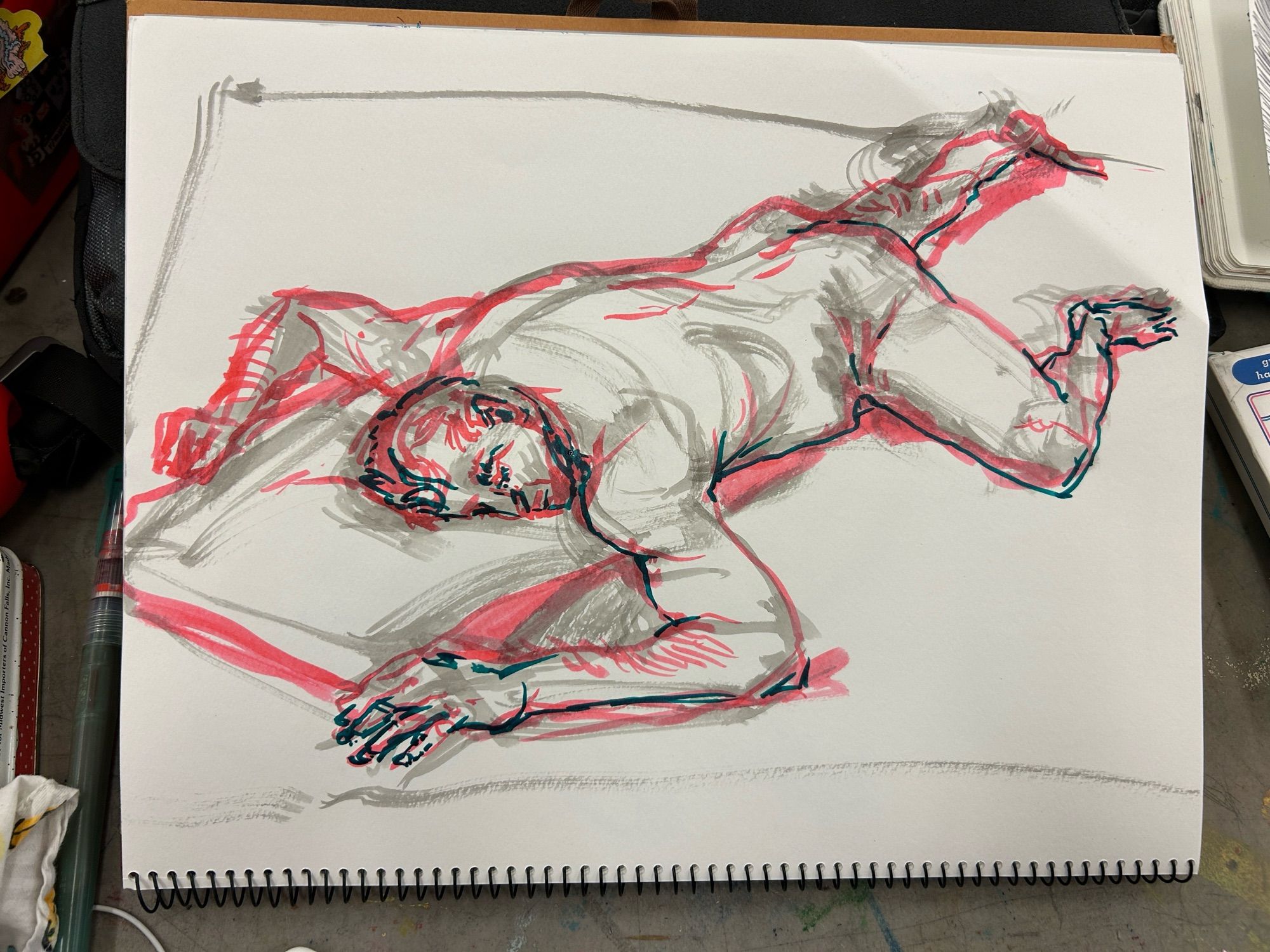 Sketch of a nude man laying face down on the ground, head resting on a pillow with his eyes closed, in red and black ink