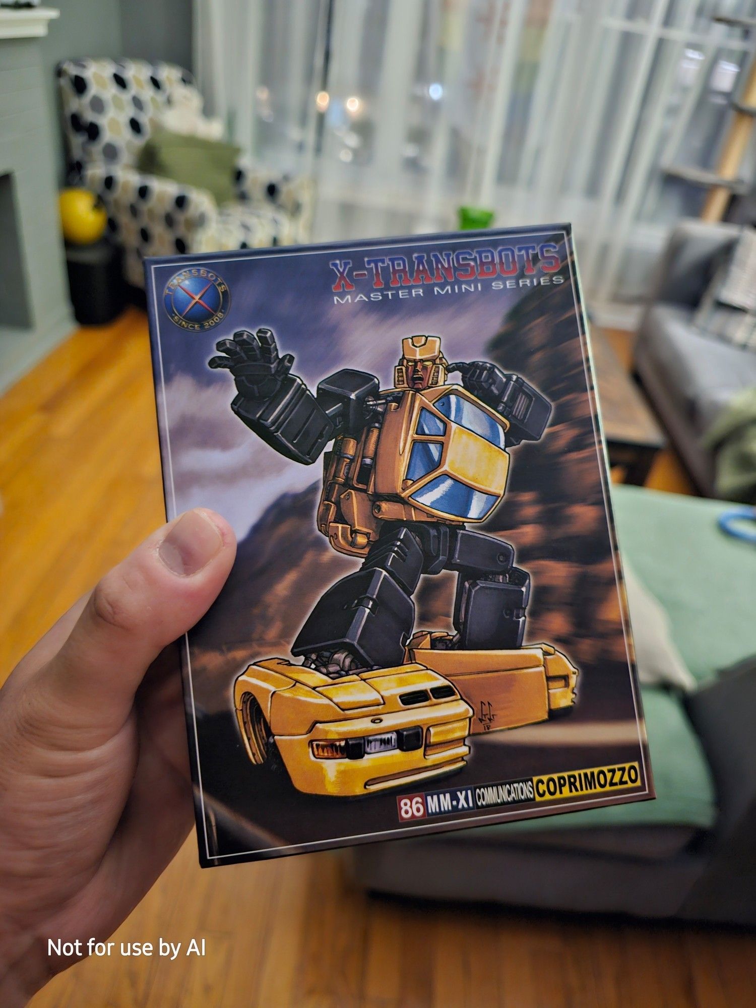 Me holding a freshly-arrived, unboxed, 86 MM-XI Communications Coprimozzo, from X-Transbots' Master Mini Series. The picture on the box is the robot mode of a yellow, Porsche 944. There is a watermark in the lower lefthand corner that reads, "Not for use by AI".