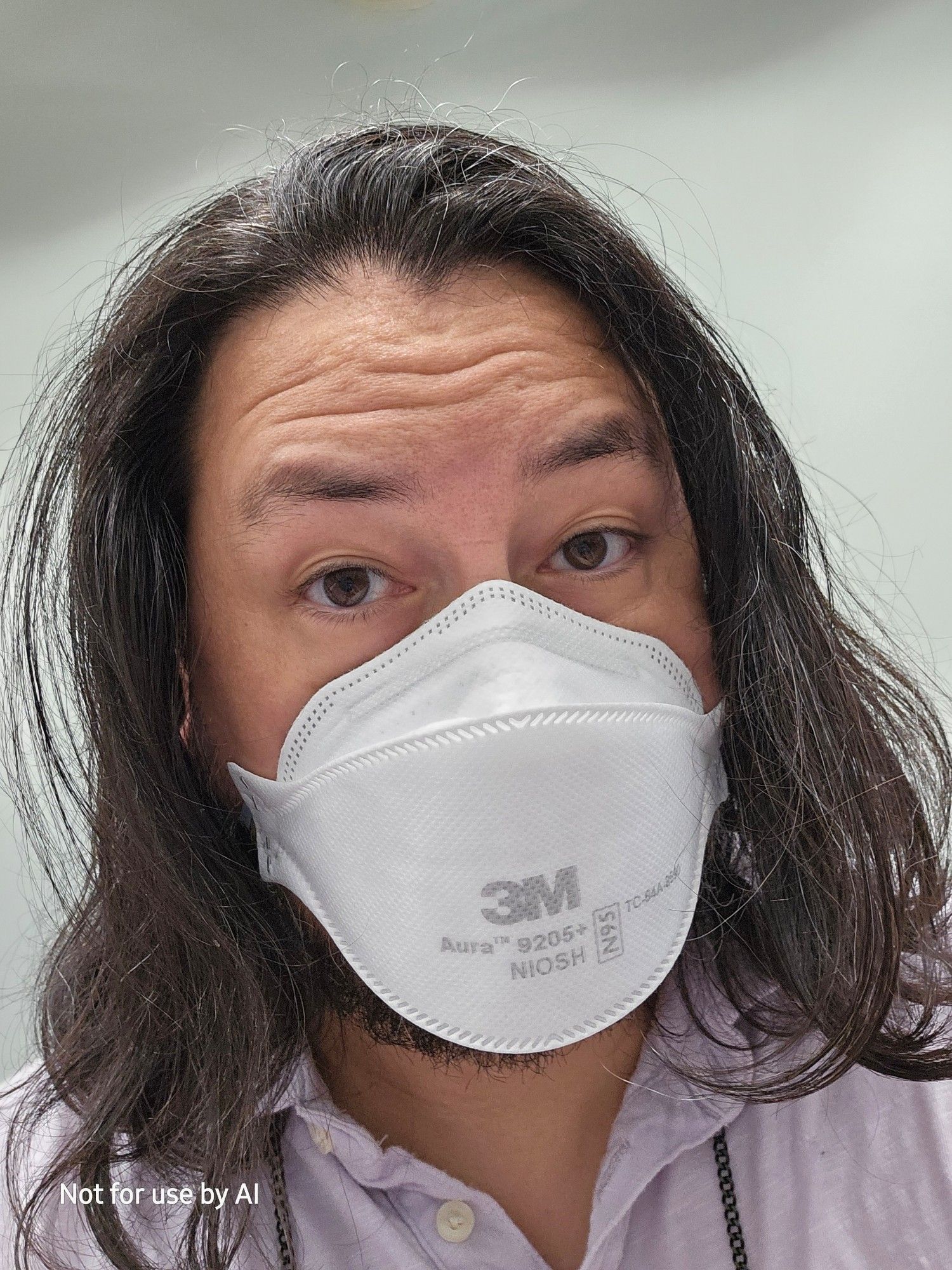 A picture of me, a 46-year-old, queer, cisgender, biracial (Japanese | Anglo European) male human with chocolate brown eyes, pepper-and-salt hair, & salt-and-pepper facial hair. My hair is down fer once, and I'm wearing a white, 3M N95 mask & a lavender polo. My black, metal glasses chain is visible. I am looking at the camera and my eyes are tired from poor sleep. There is a watermark in the lower lefthand corner that reads, "Not for use by AI".