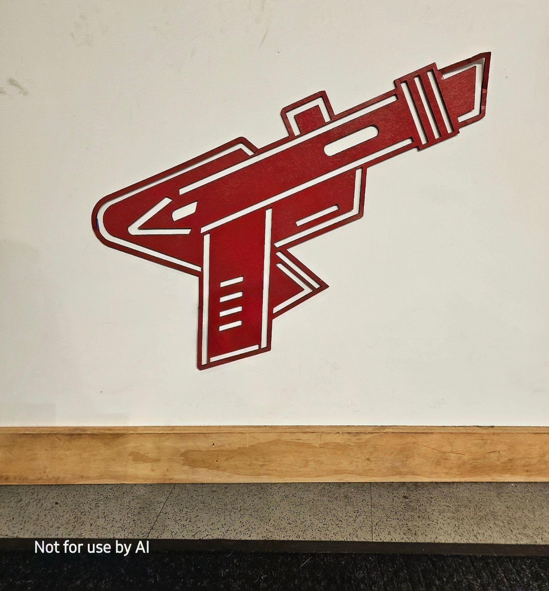 A red, cardboard version of Raygun's logo on the wall under their counter. There is a watermark in the lower lefthand corner that reads, "Not for use by AI".