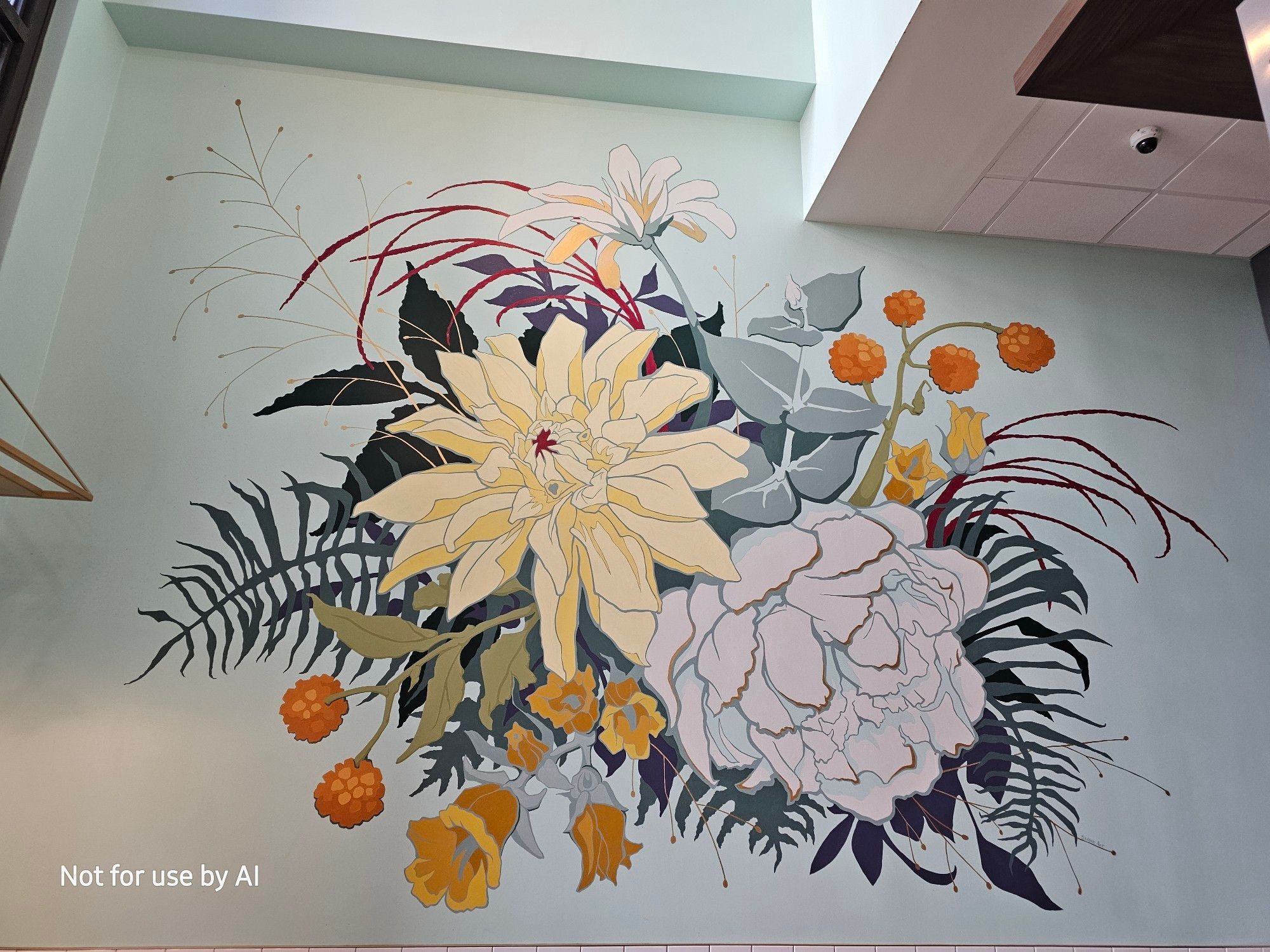 A large mural of flowers and leaves painted on the wall of Goddess & Baker in the Loop. There is a watermark in the lower lefthand corner that reads, "Not for use by AI".