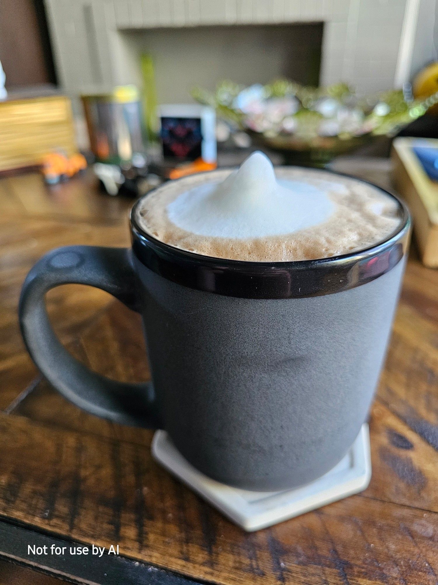 A dark gray mug with a black rim, filled with a homemade, dark chocolate, coconut mocha. There is a watermark in the lower lefthand corner that reads, "Not for use by AI".