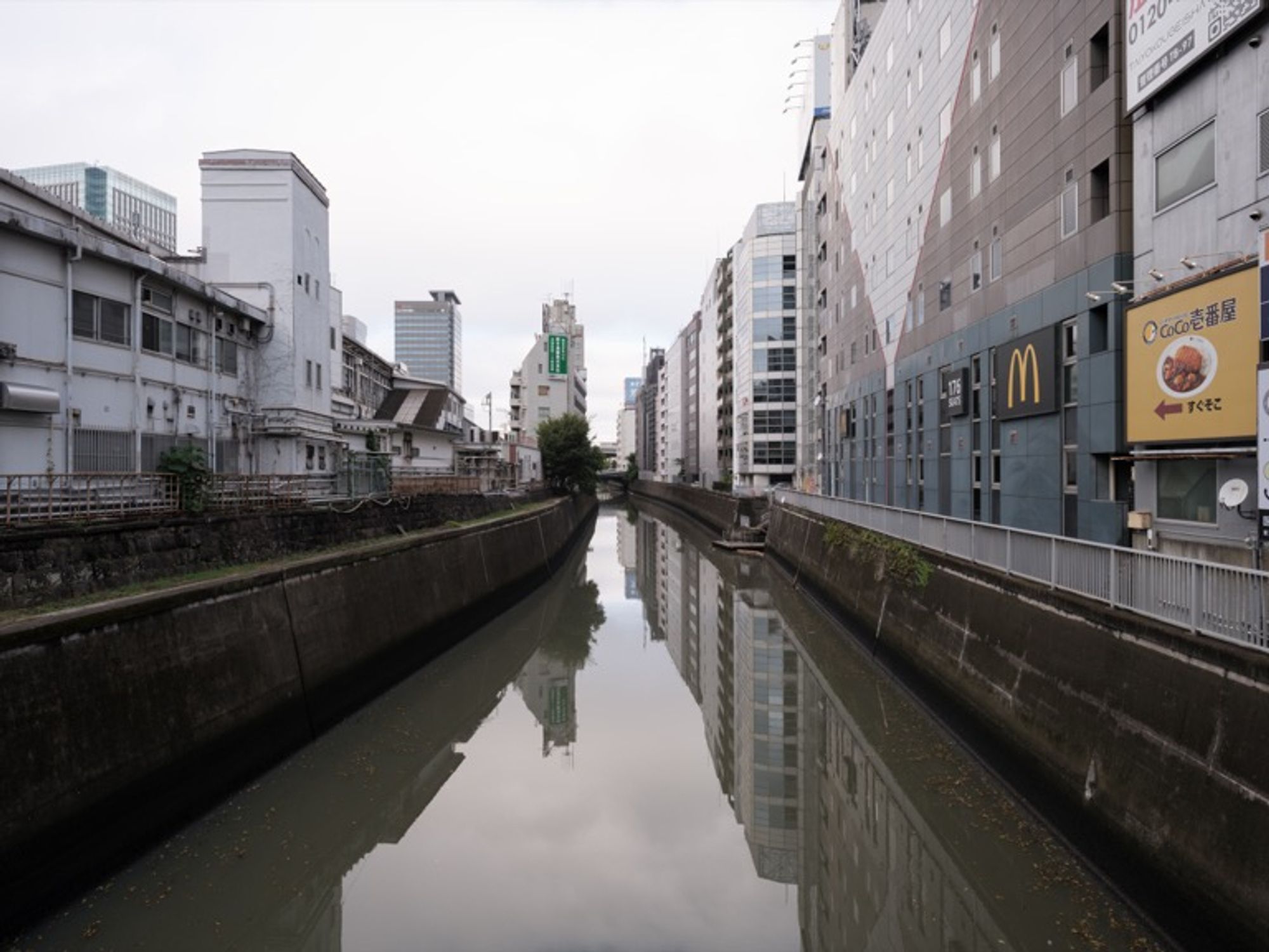 Muddy river quietly flowing through the gaps of the city. This image was captured using the GFX100S camera, equipped with the GF23mmF4 R LM WR lens (wide-angle prime lens).